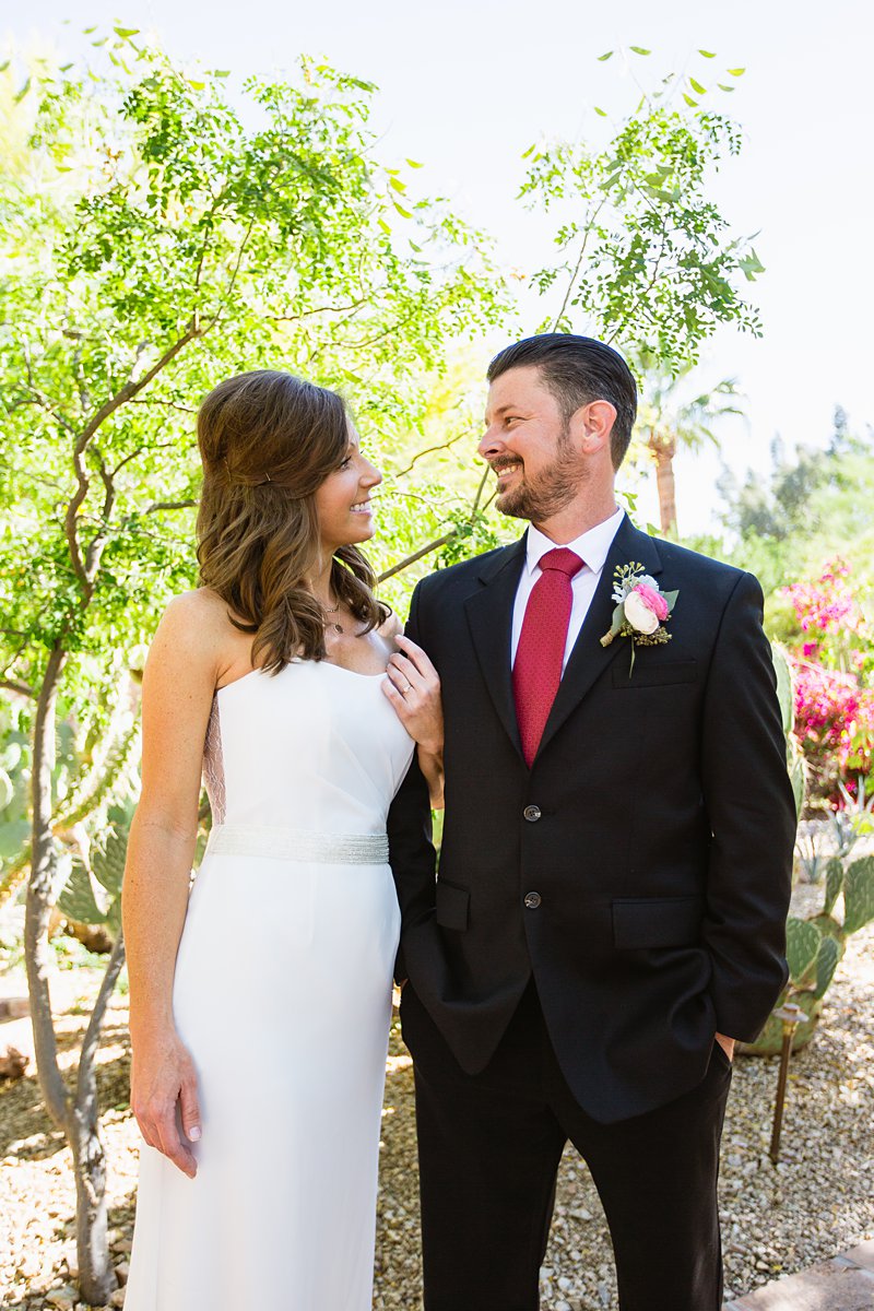 Bride and groom look at each other in a desert garden by PMA Photography.