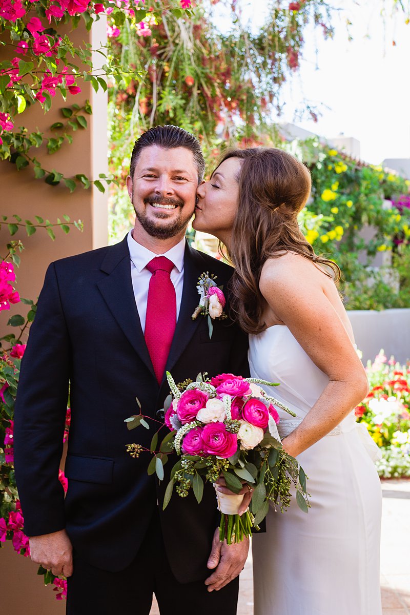 Classic pink bride kissing groom's cheek by Arizona wedding photographer PMA Photography.