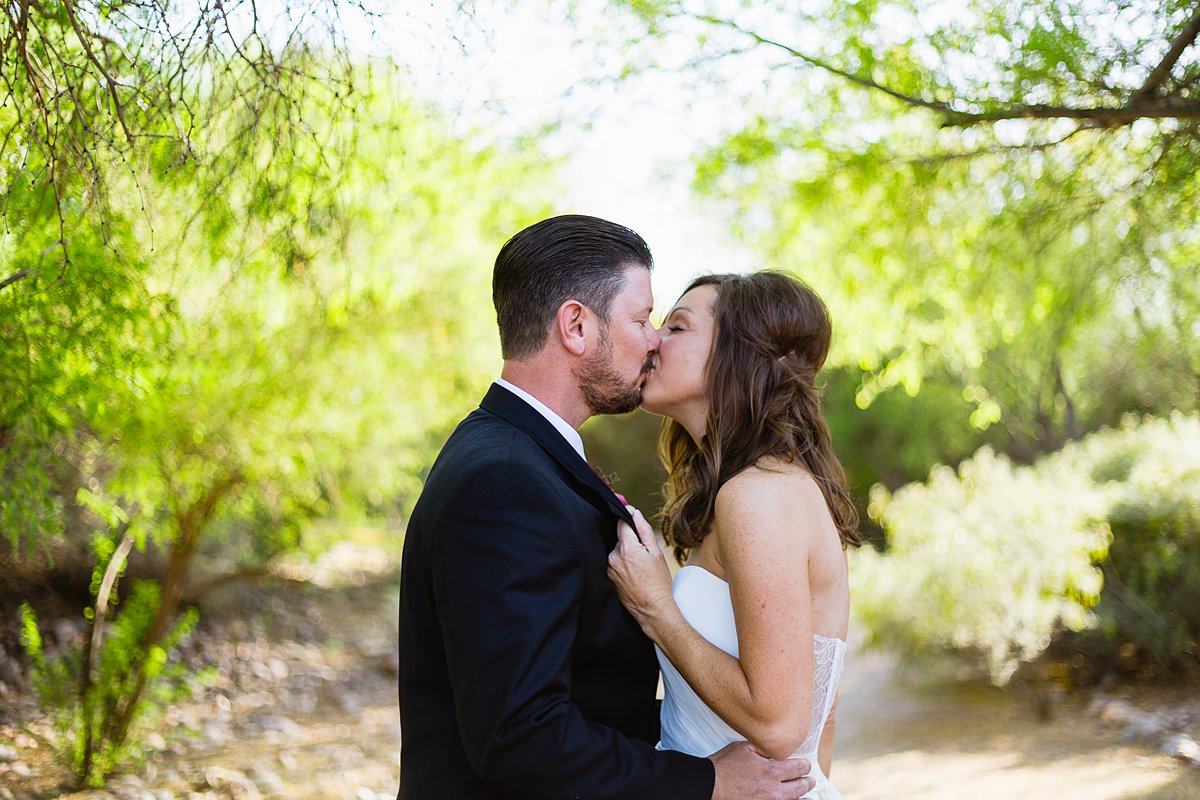 Bride pulls her groom in for a kiss by Arizona wedding photographers PMA Photography.