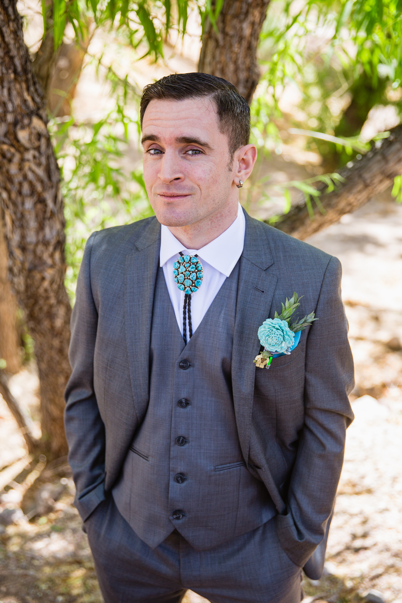 Groom in a grey quit with turquoise details and bolo tie by Arizona wedding photographer PMA Photography.