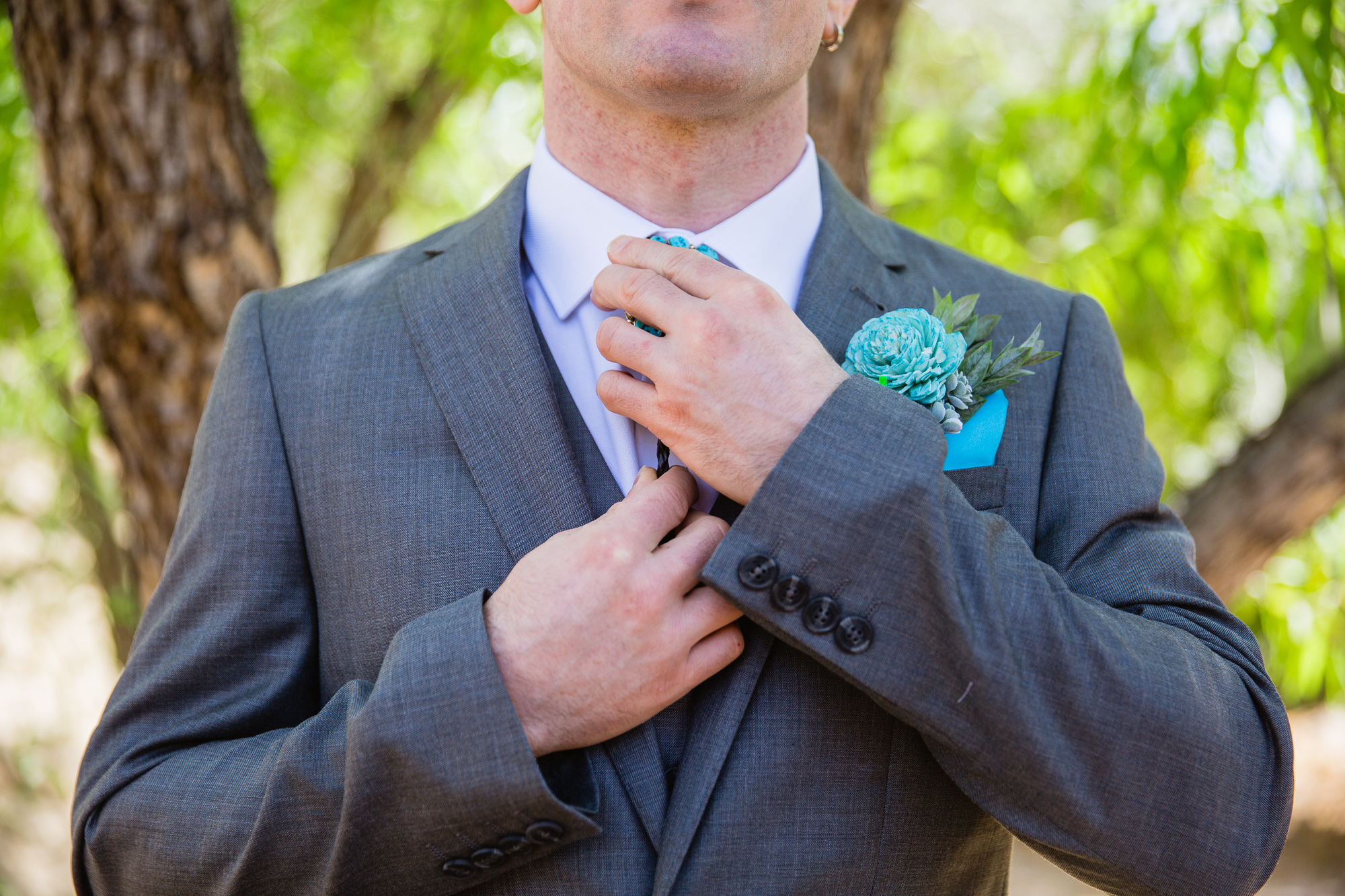 Groom adjusting his bolo tie while getting ready for his wedding by Arizona wedding photographer PMA Photography.