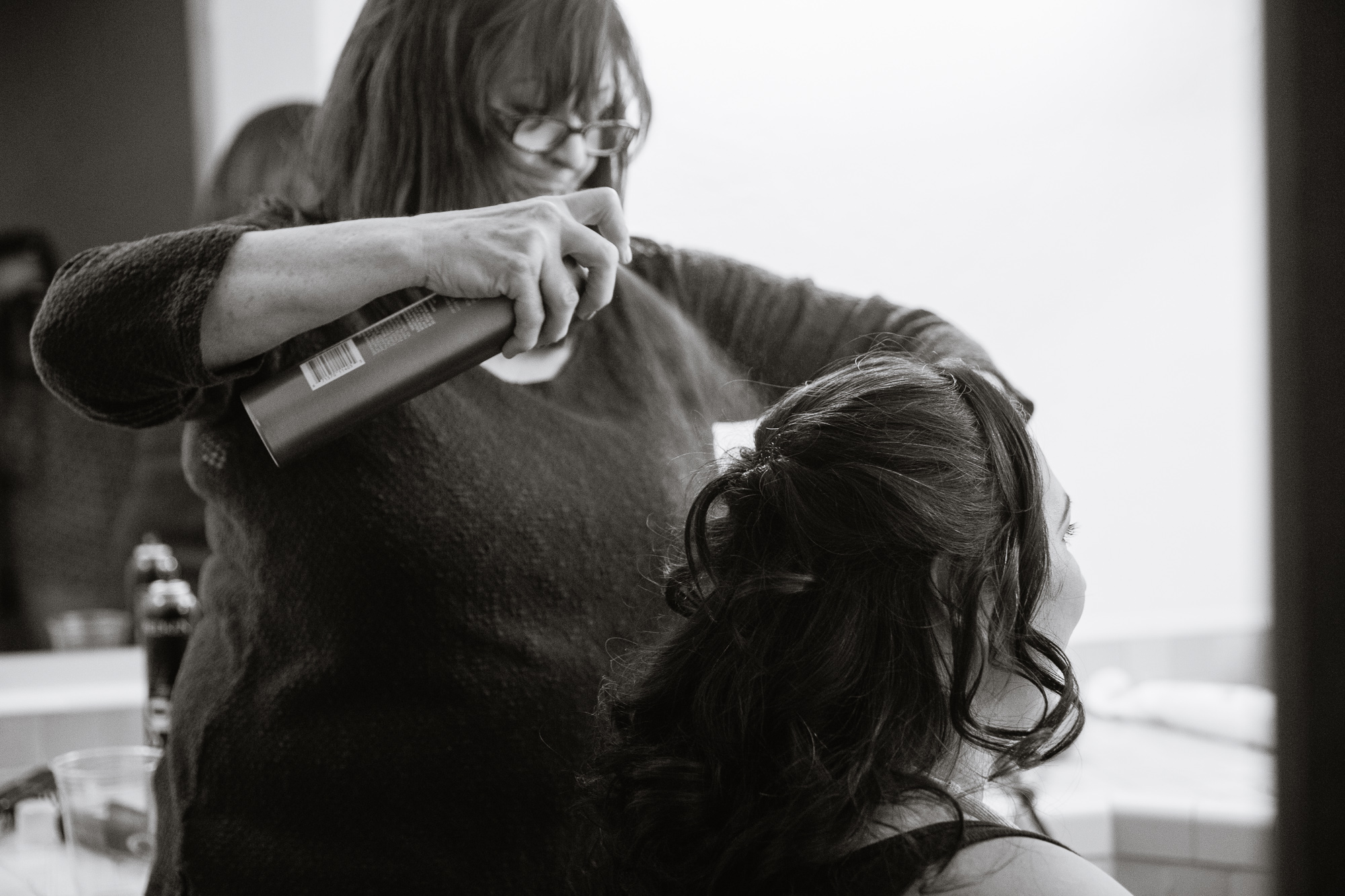 Black and white image of bride's mother doing her hair on her wedding day by Arizona wedding photographers PMA Photography.