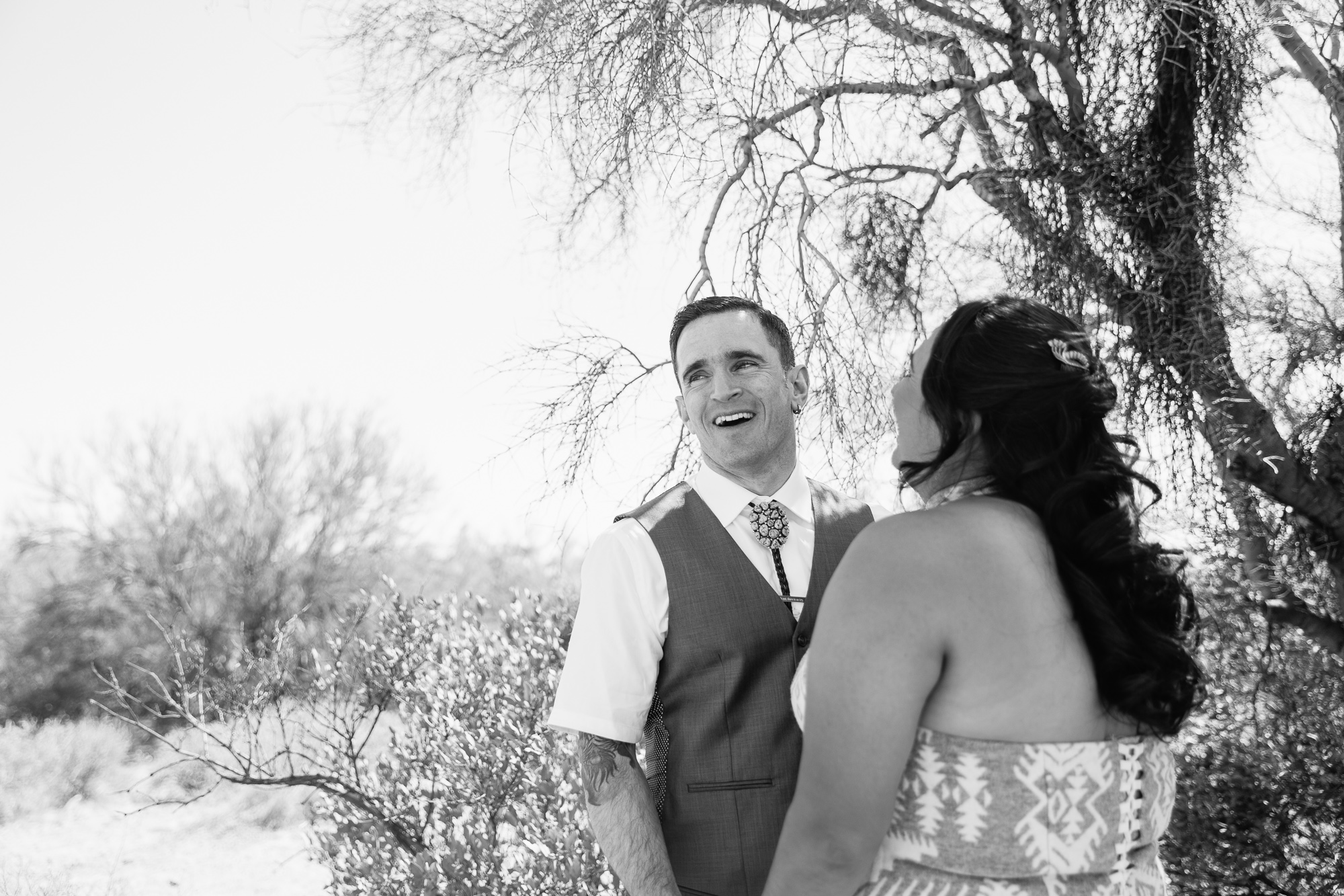 Bride and groom sharing a laugh at Lost Dutchman State Park by Arizona wedding photographers PMA Photography.