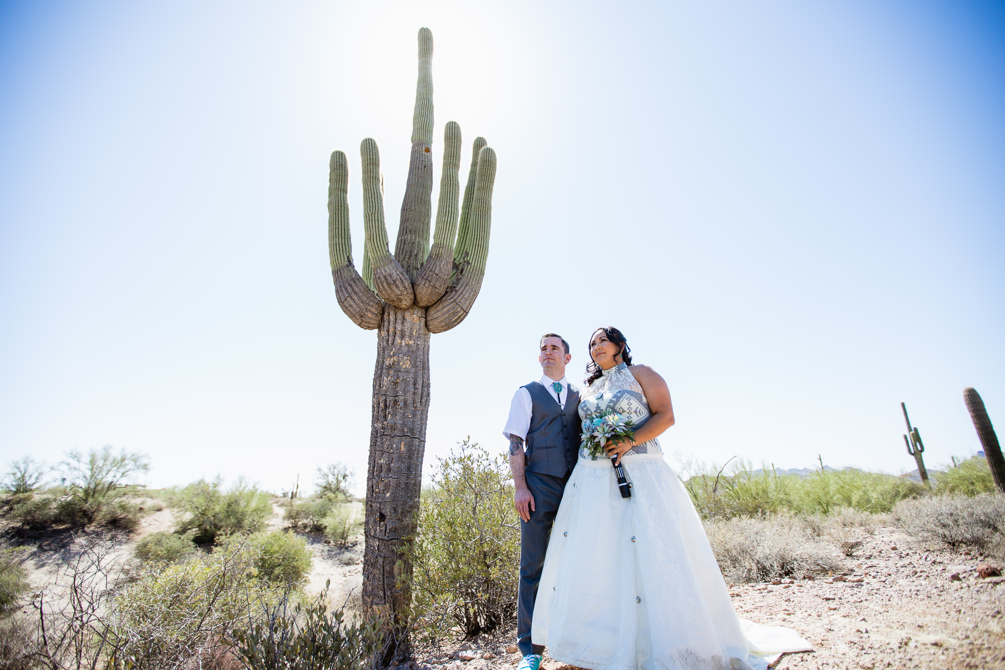 Tattooed Irish groom and Navajo bride in front of a Saguaro cactus at their Lost Dutchman State Park Turquoise Star Wars wedding by Phoenix wedding photographers PMA Photography.