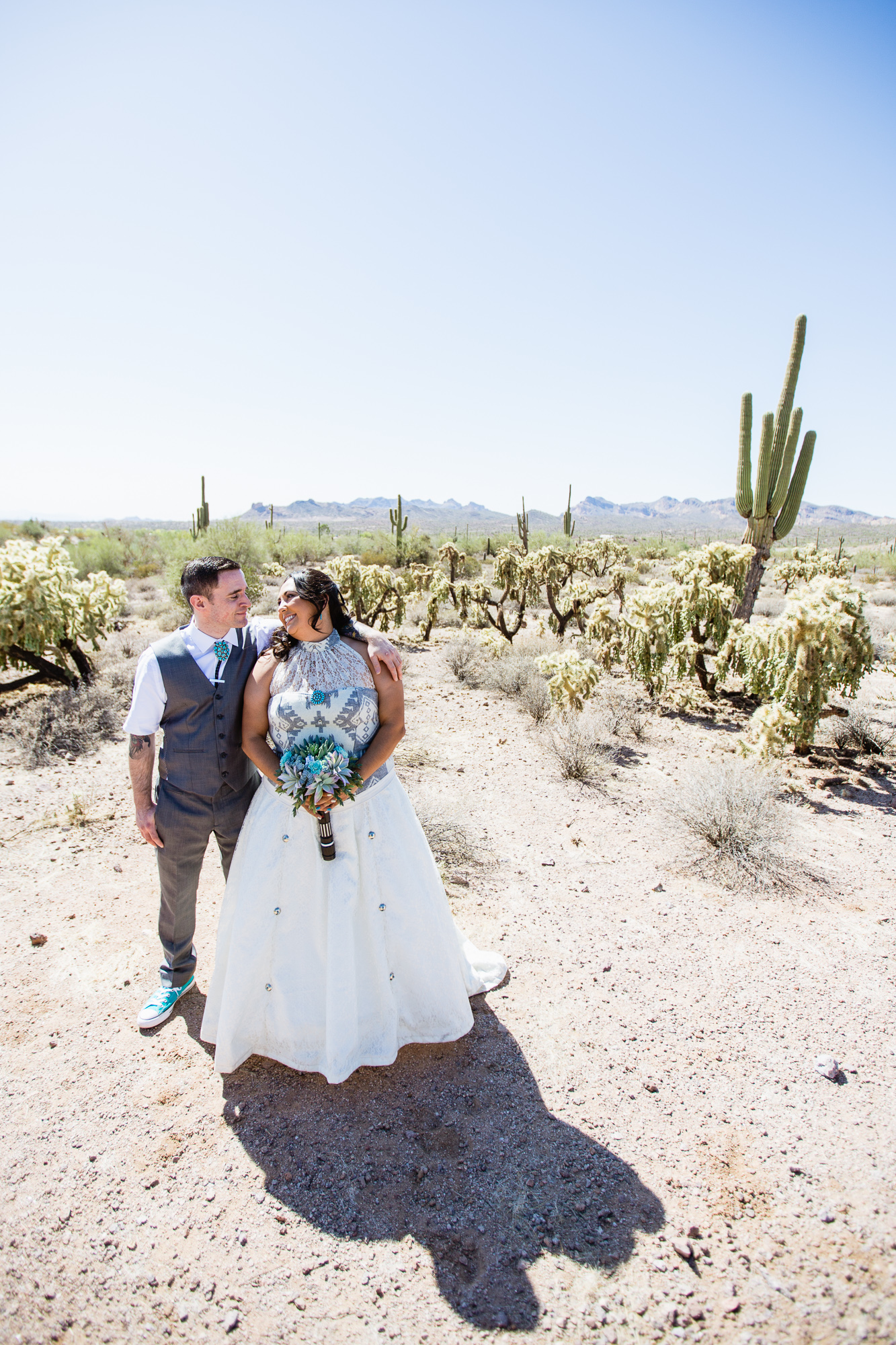 Bride and groom in turquoise and grey wedding attire in the Arizona desert at Lost Dutchman State Park by wedding photographers PMA Photography.