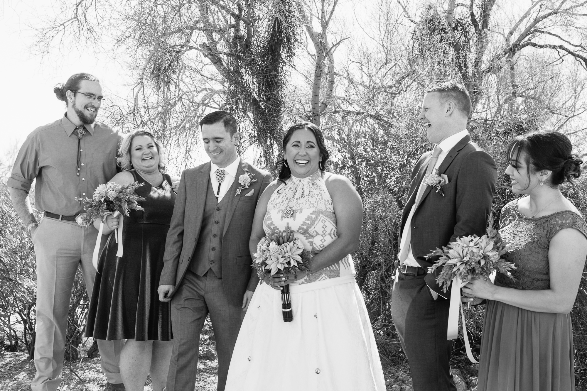 Black and white image of bridal party sharing a laugh by Arizona wedding photographers PMA Photography.