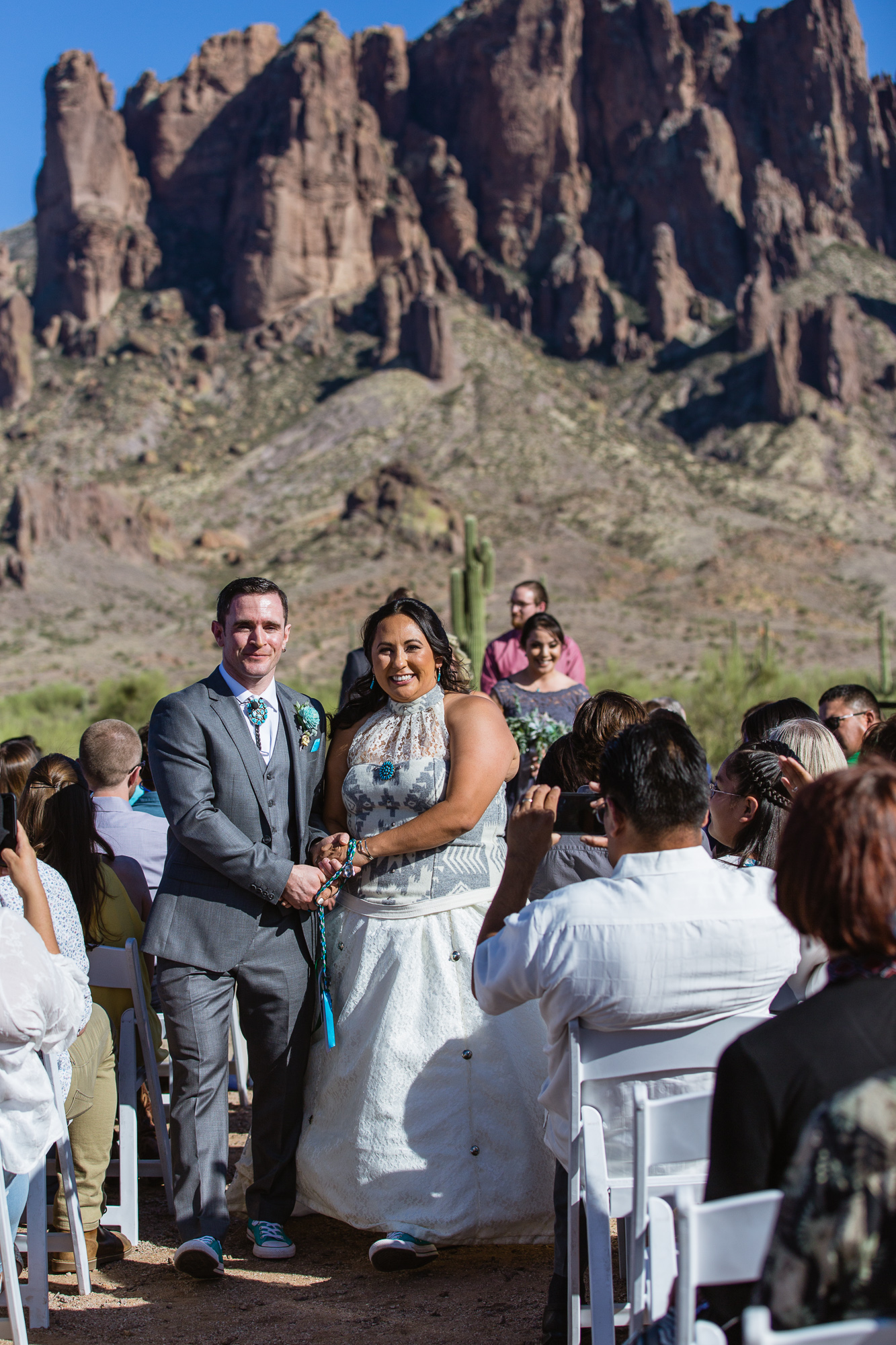 Bride and groom walking down the aisle with their hands fastened during a Lost Dutchman State Park wedding ceremony by Arizona wedding photographers PMA Photography.