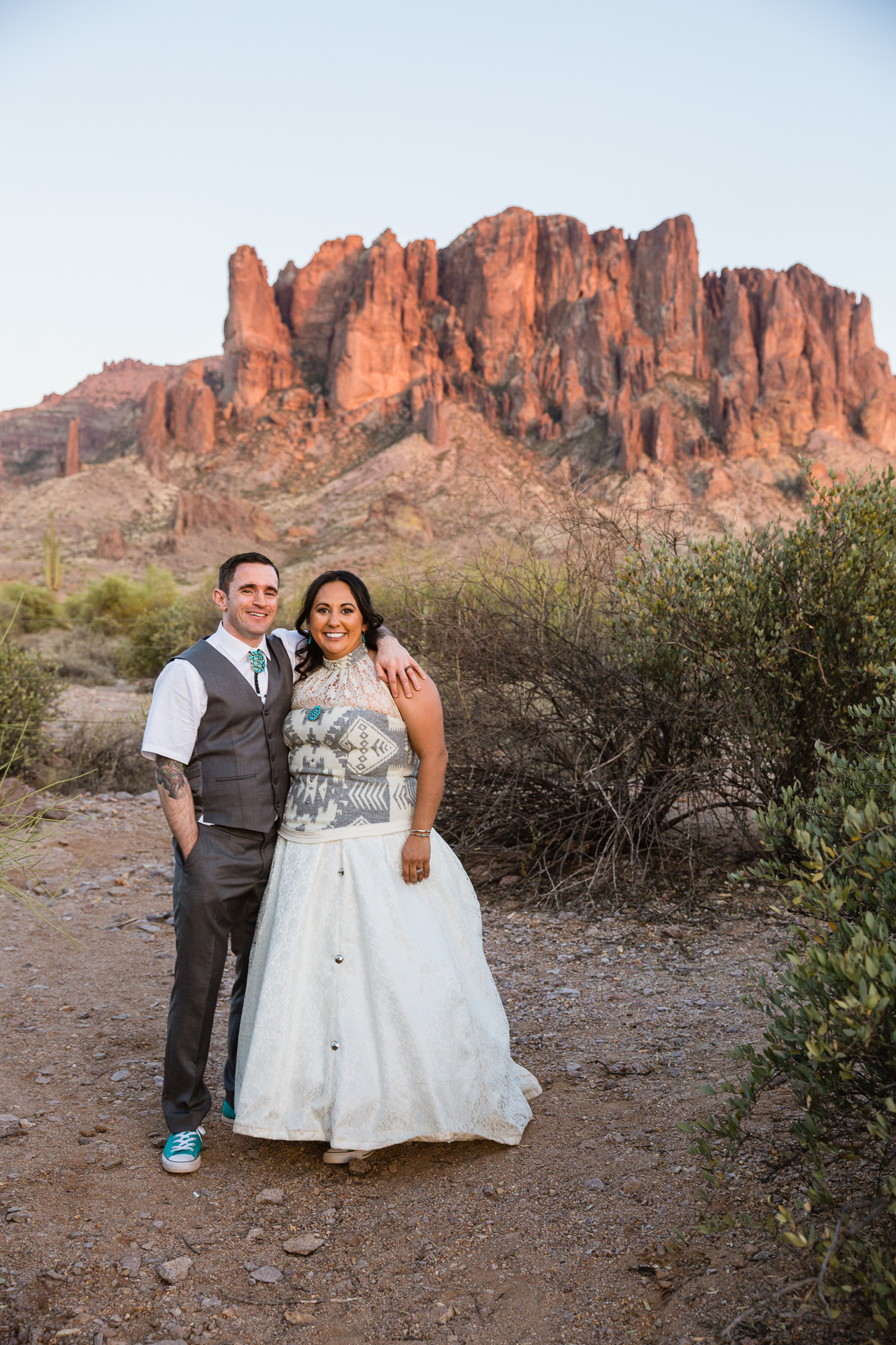 Tattooed groom and bride in Navajo dress at the superstition mountains at Lost Dutchman state park by Arizona wedding photographer PMA Photography.