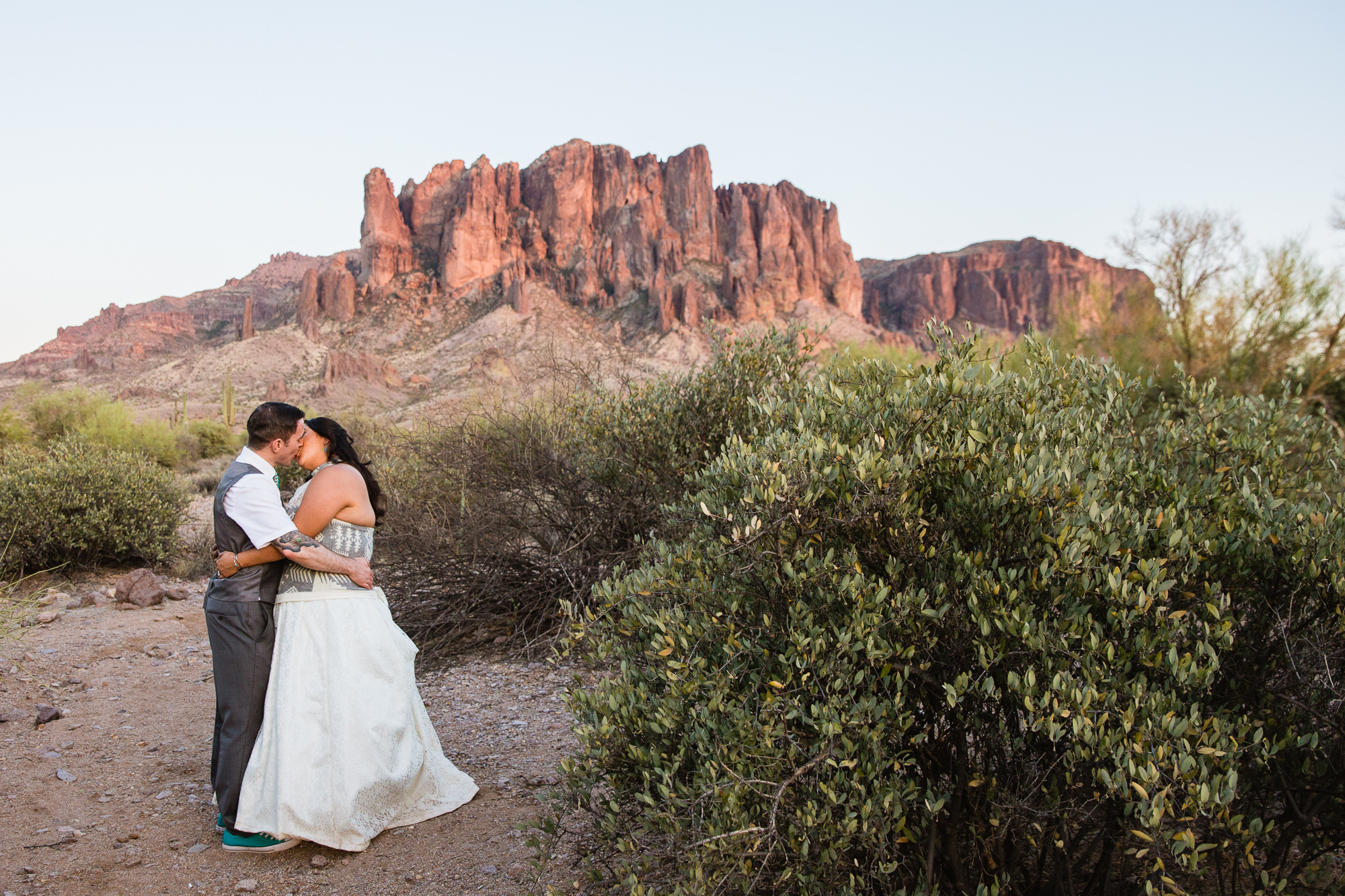 Tattooed groom and bride in Navajo dress at the superstition mountains at Lost Dutchman state park by Arizona wedding photographer PMA Photography.
