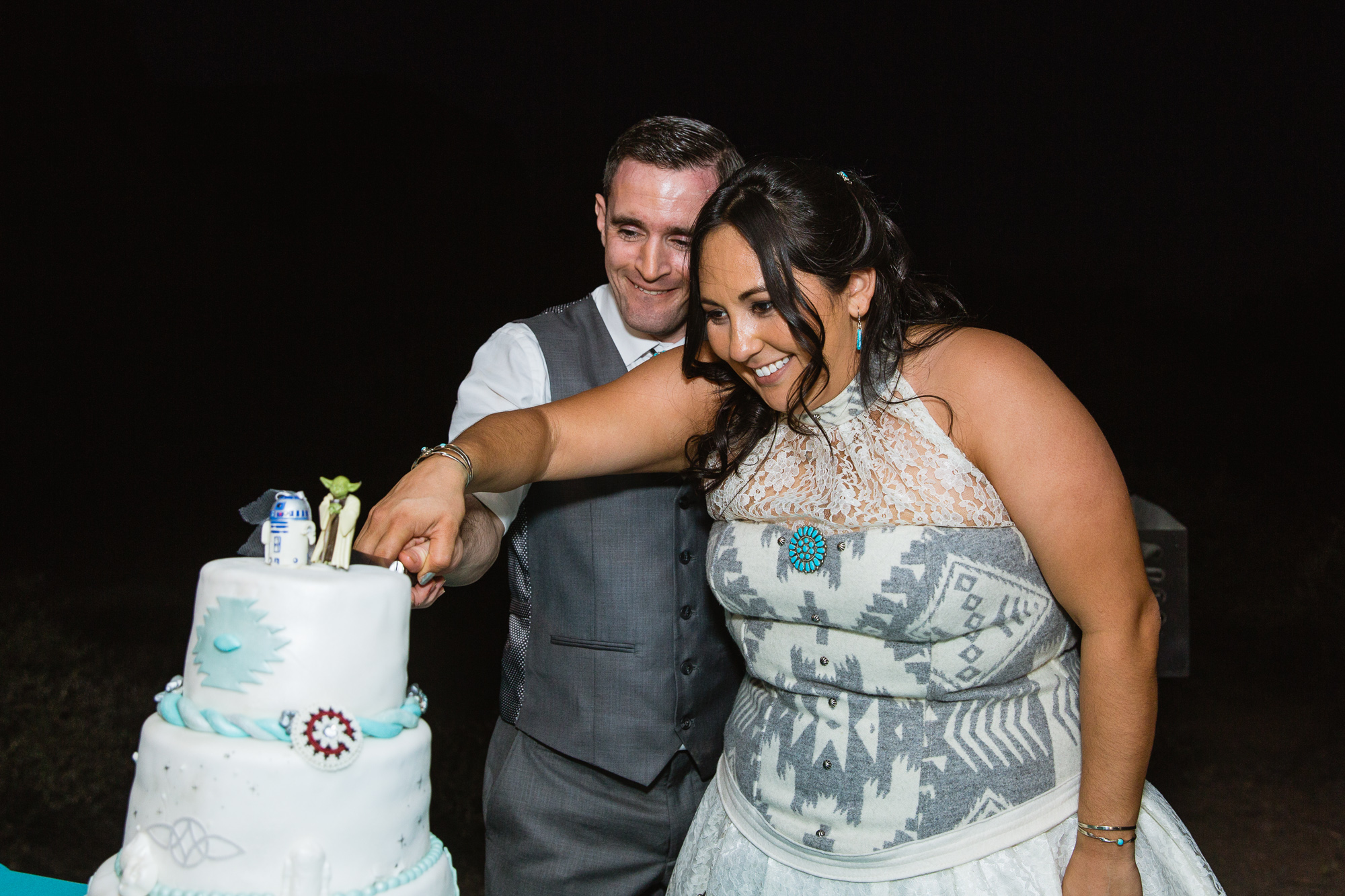 Bride and groom cutting the cake at their wedding reception by PMA Photography.