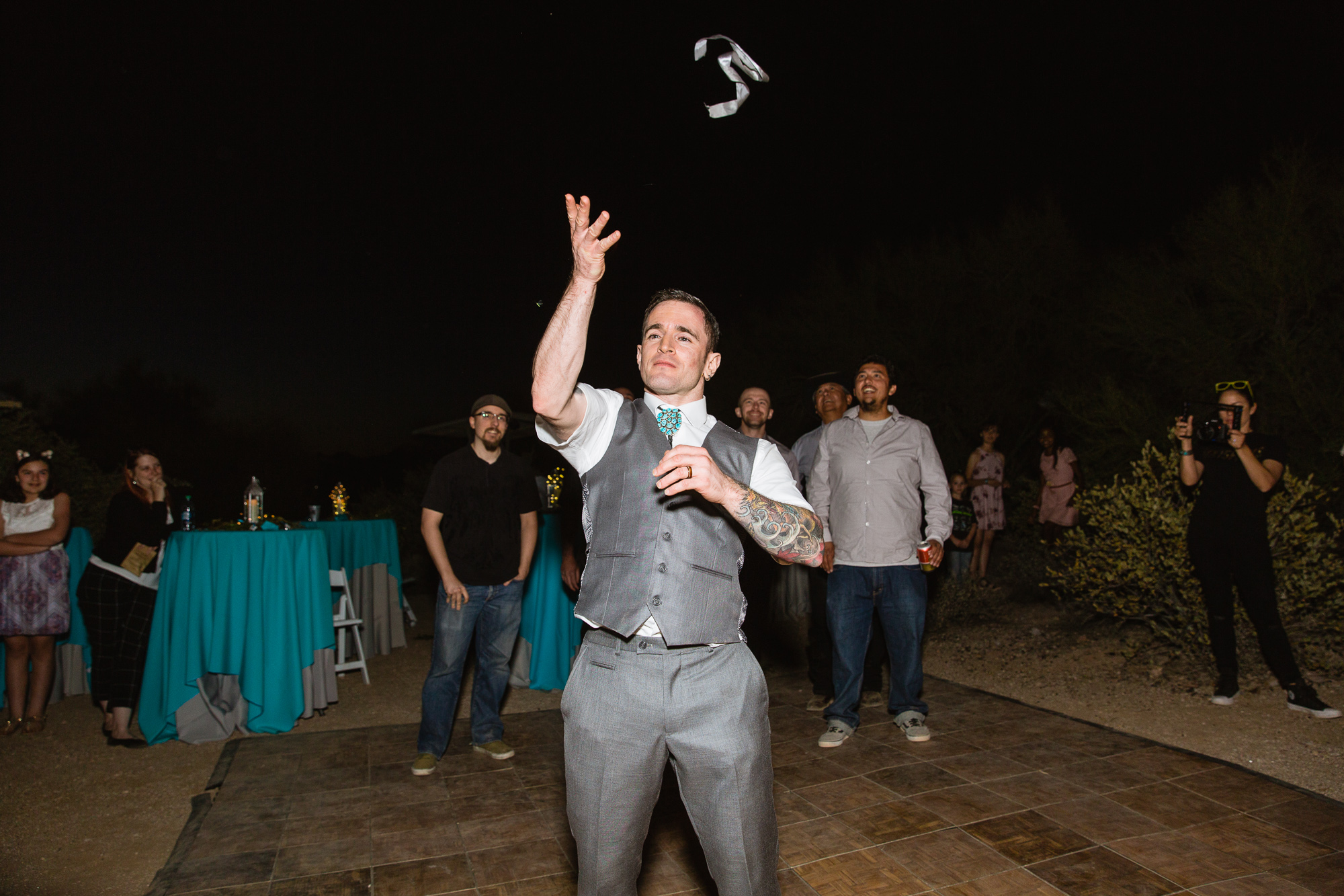 Groom doing the garter toss by PMA Photography.
