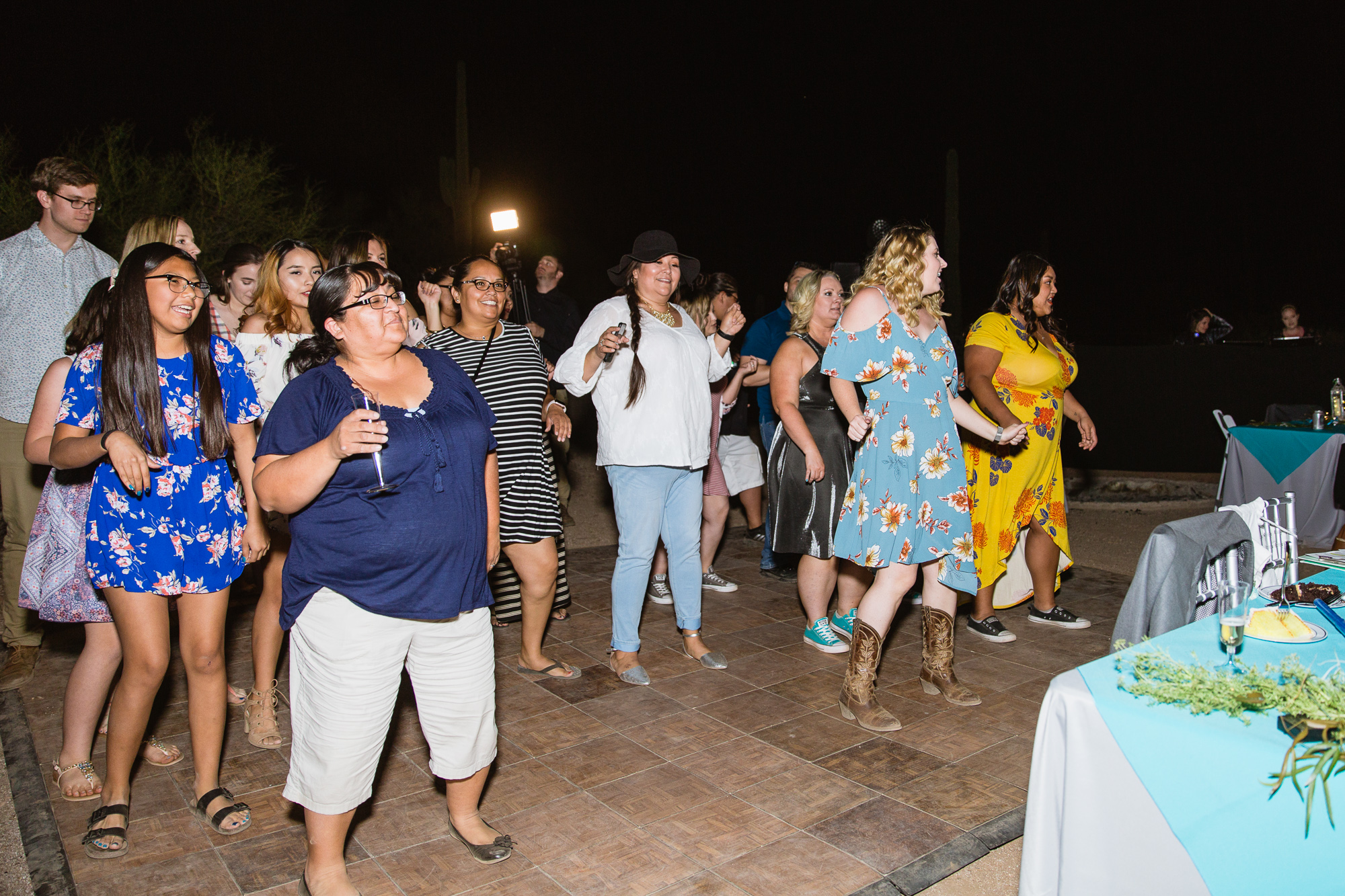 Guests line dancing at a wedding reception by wedding photographer PMA Photography.