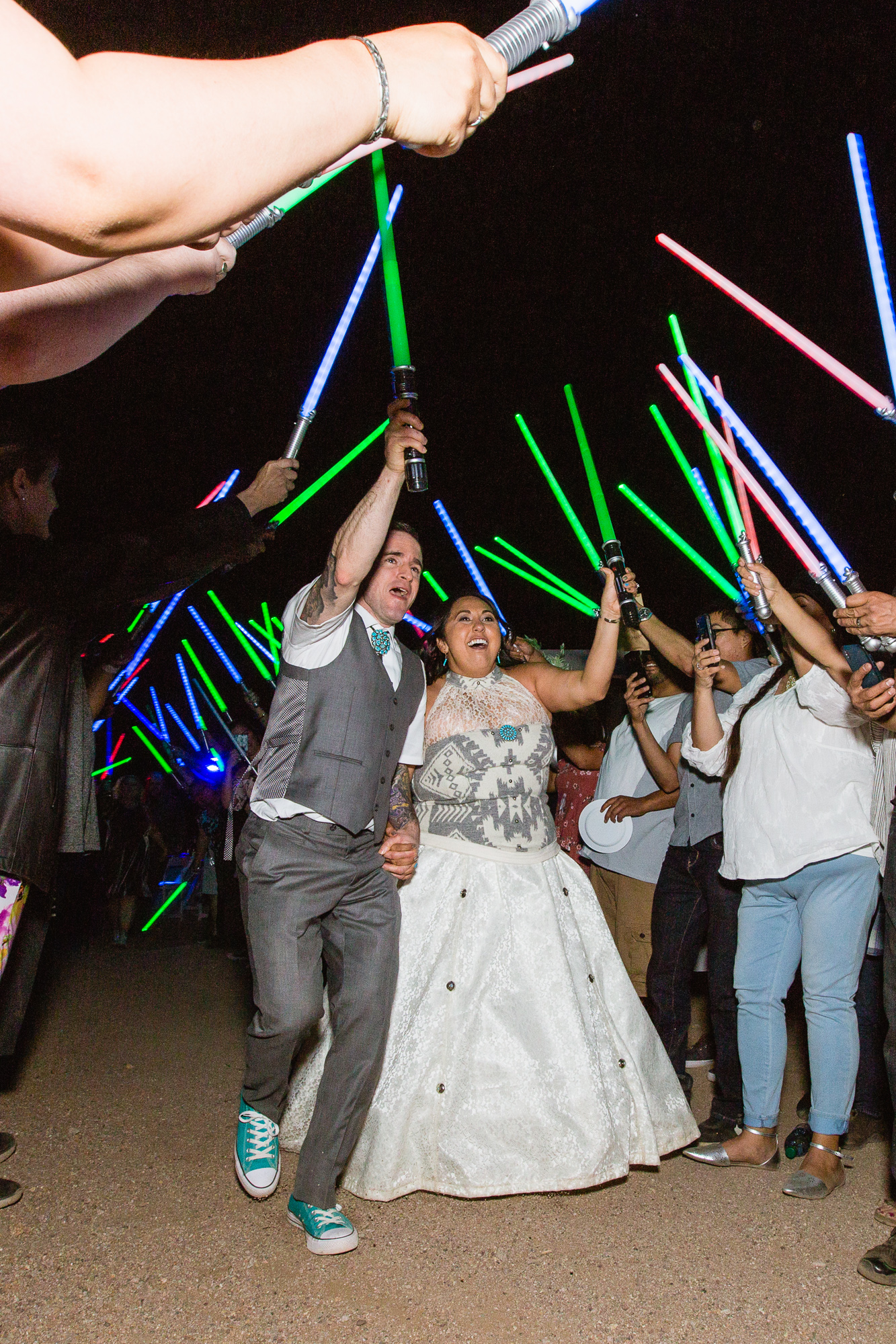 Bride and groom walk through saluted lightsabers for their grand exit at their Star Wars themed wedding by Arizona wedding photographer PMA Photography.