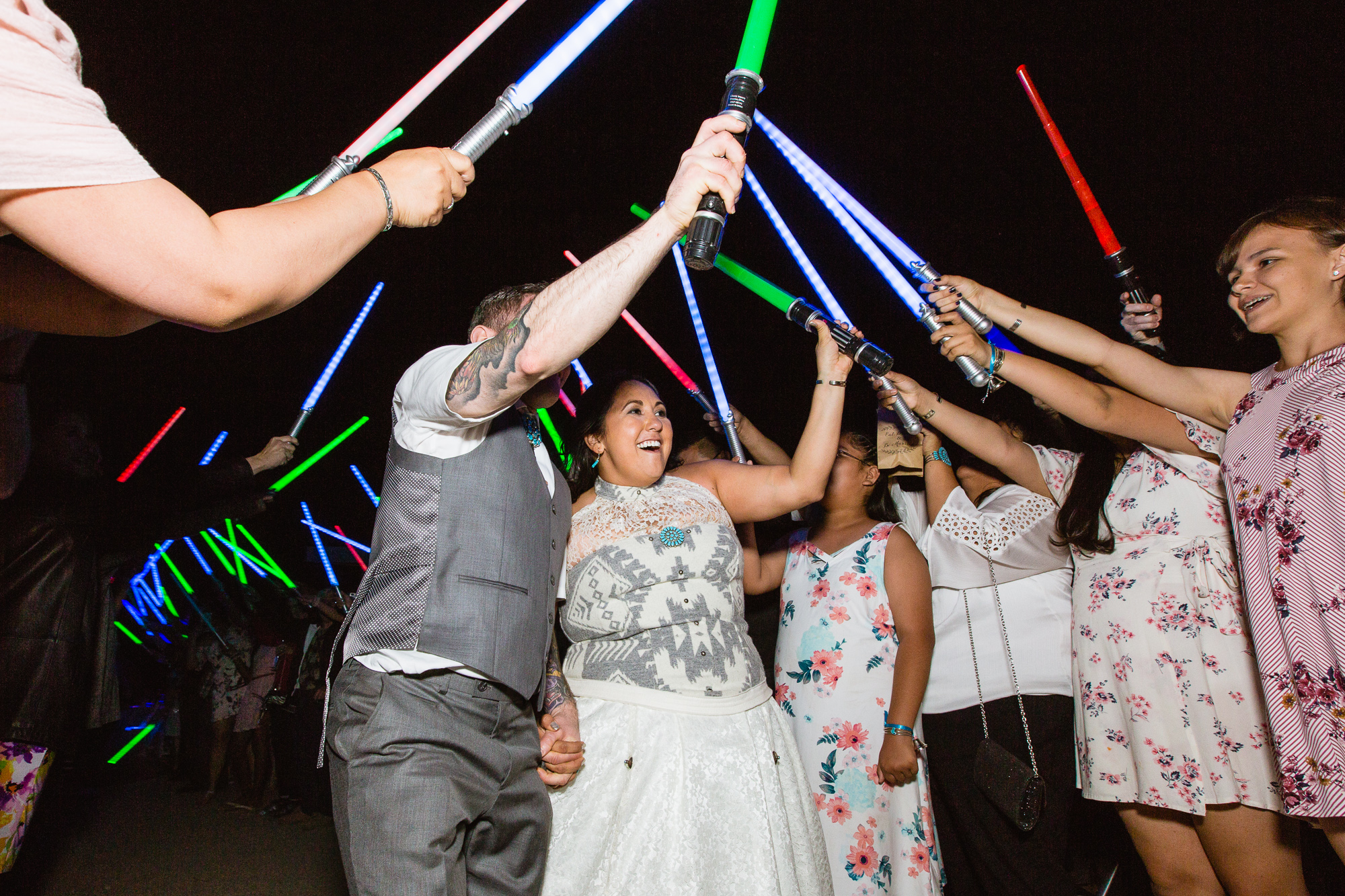Bride and groom walk through saluted lightsabers for their grand exit at their Star Wars themed wedding by Arizona wedding photographer PMA Photography.