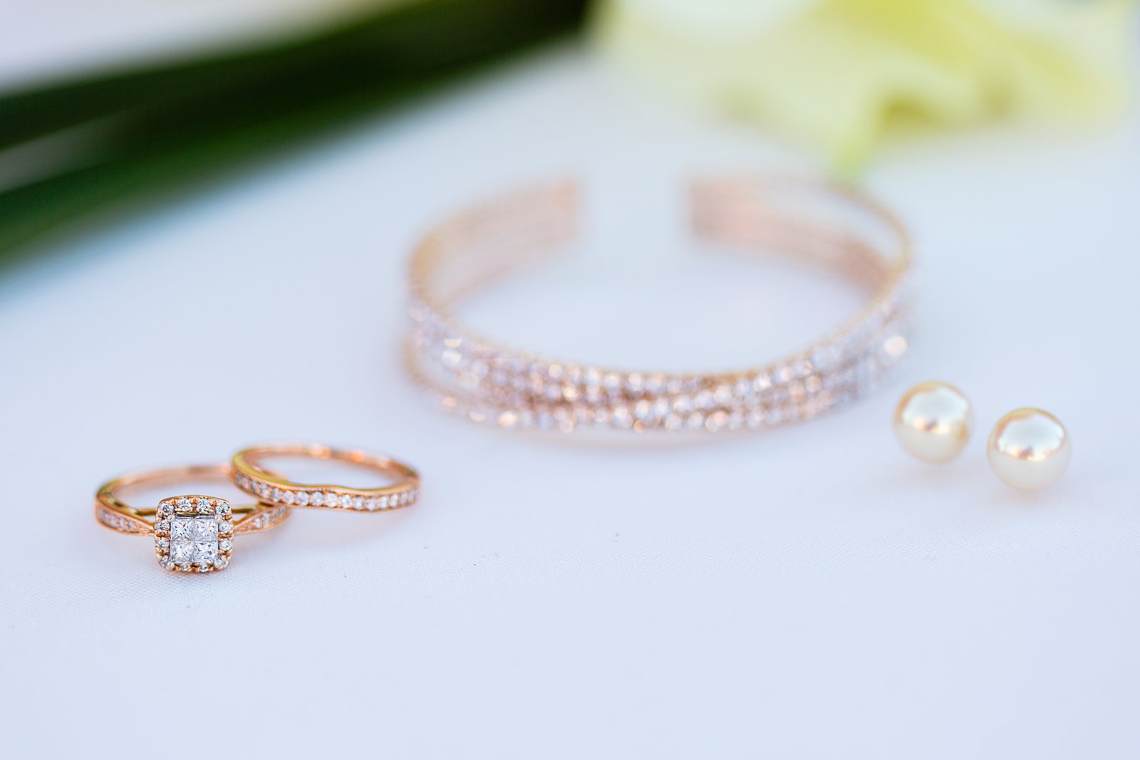 Brides's wedding day details of rose gold, diamond, and pearl bridal jewelry by PMA Photography.