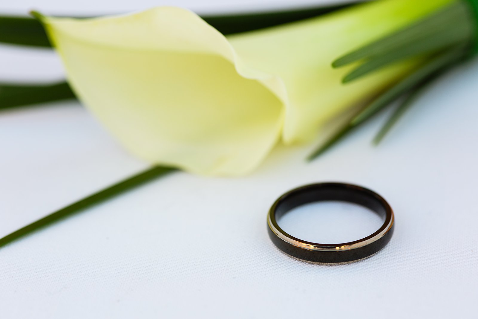 Groom's black and gold simple wedding band with calla lily boutonniere by PMA Photography.