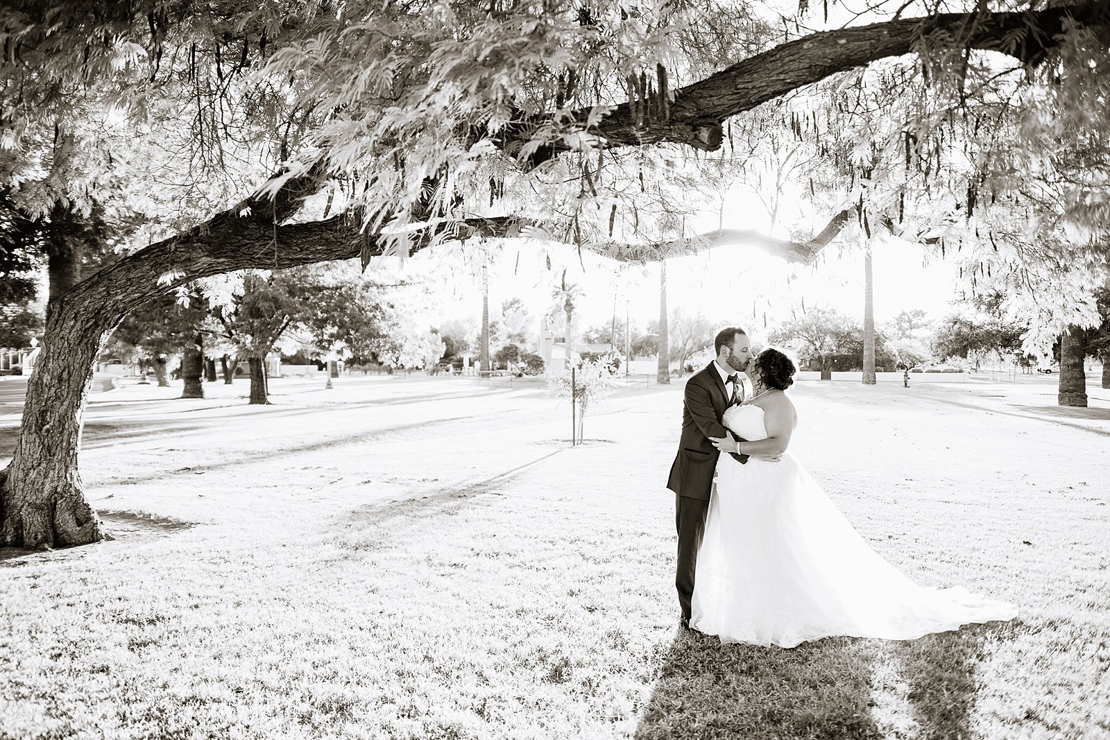 Bride and groom share a kiss during their Encanto Park wedding by Arizona wedding photographer PMA Photography.