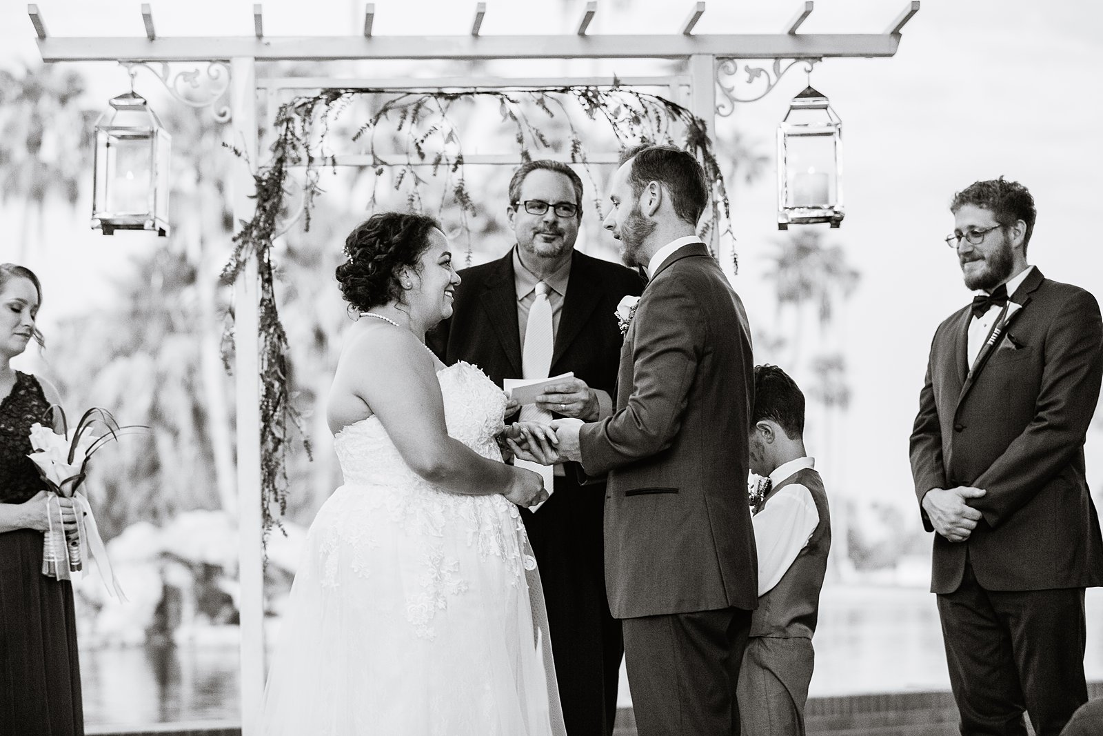 Bride and groom exchange rings during their wedding ceremony at Encanto Park by Arizona wedding photographer PMA Photography.