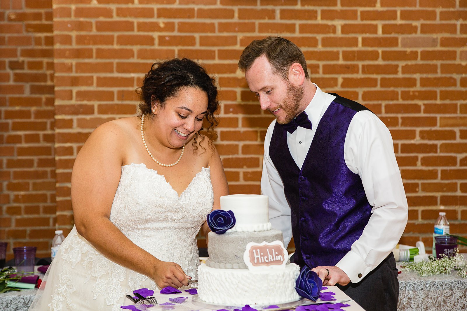 Bride and groom cutting their wedding cake at their Encanto Park wedding reception by Arizona wedding photographer PMA Photography.