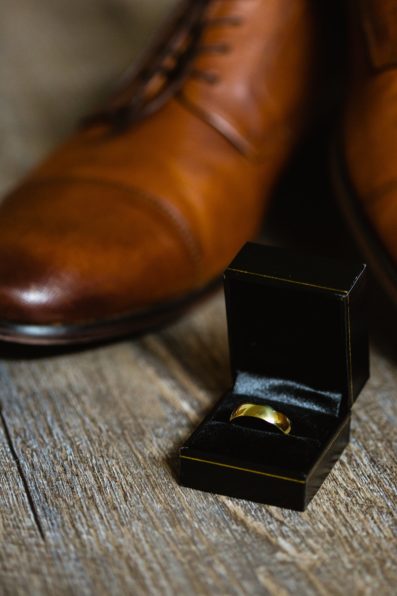 Groom's wedding day details of a simple golden wedding band in front of his tan leather shoes by PMA Photography.