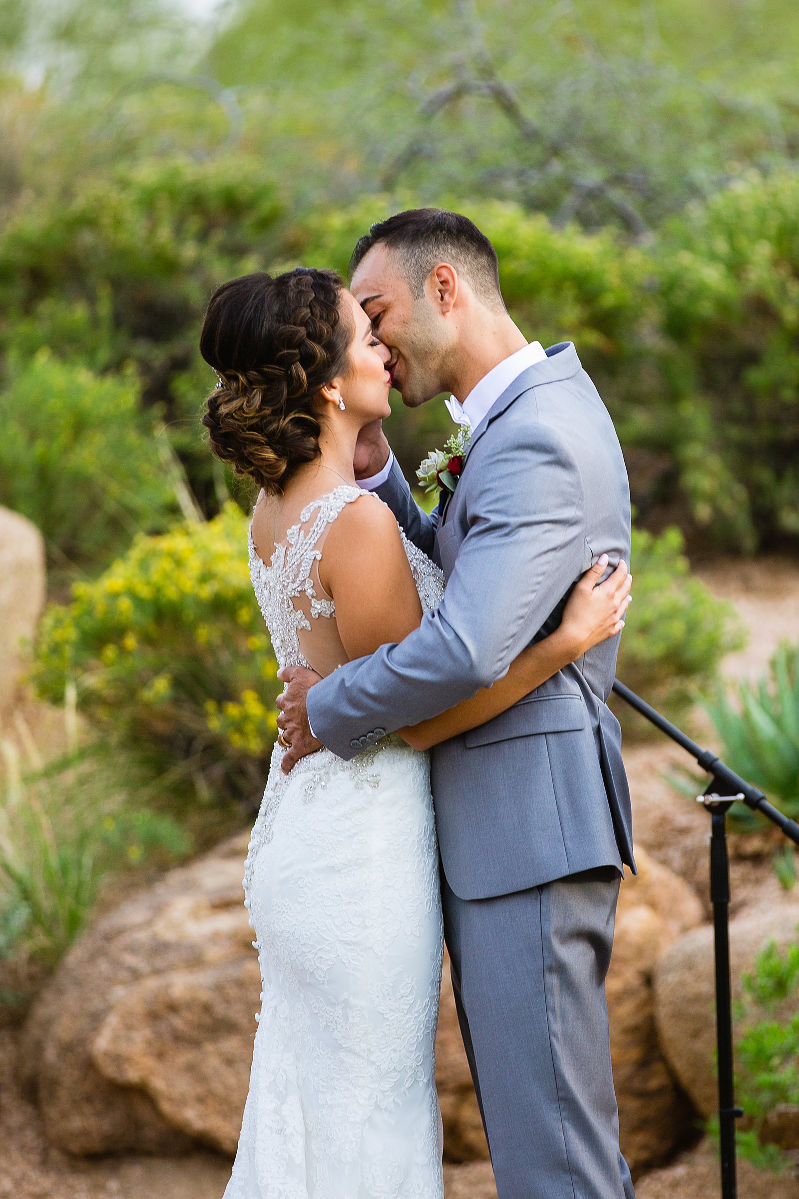 Bride and groom share their first kiss during their wedding ceremony at Troon North by Arizona wedding photographer PMA Photography.
