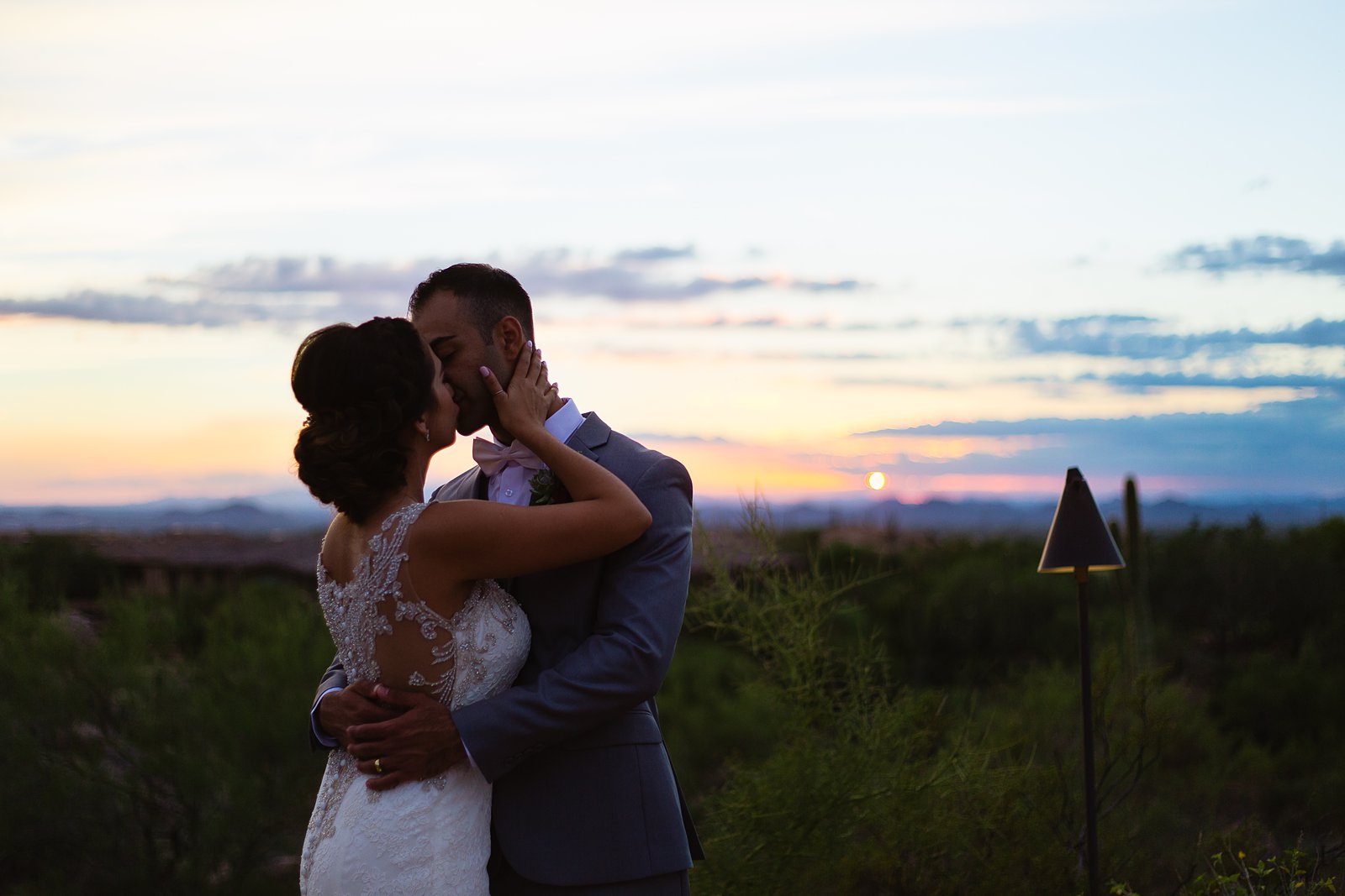 Bride and groom share a kiss as the sun sets during their Troon North wedding by Arizona wedding photographer PMA Photography.