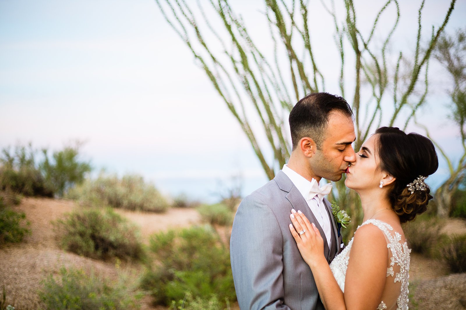 Bride and groom share a kiss during their Troon North wedding by Scottsdale wedding photographer PMA Photography.