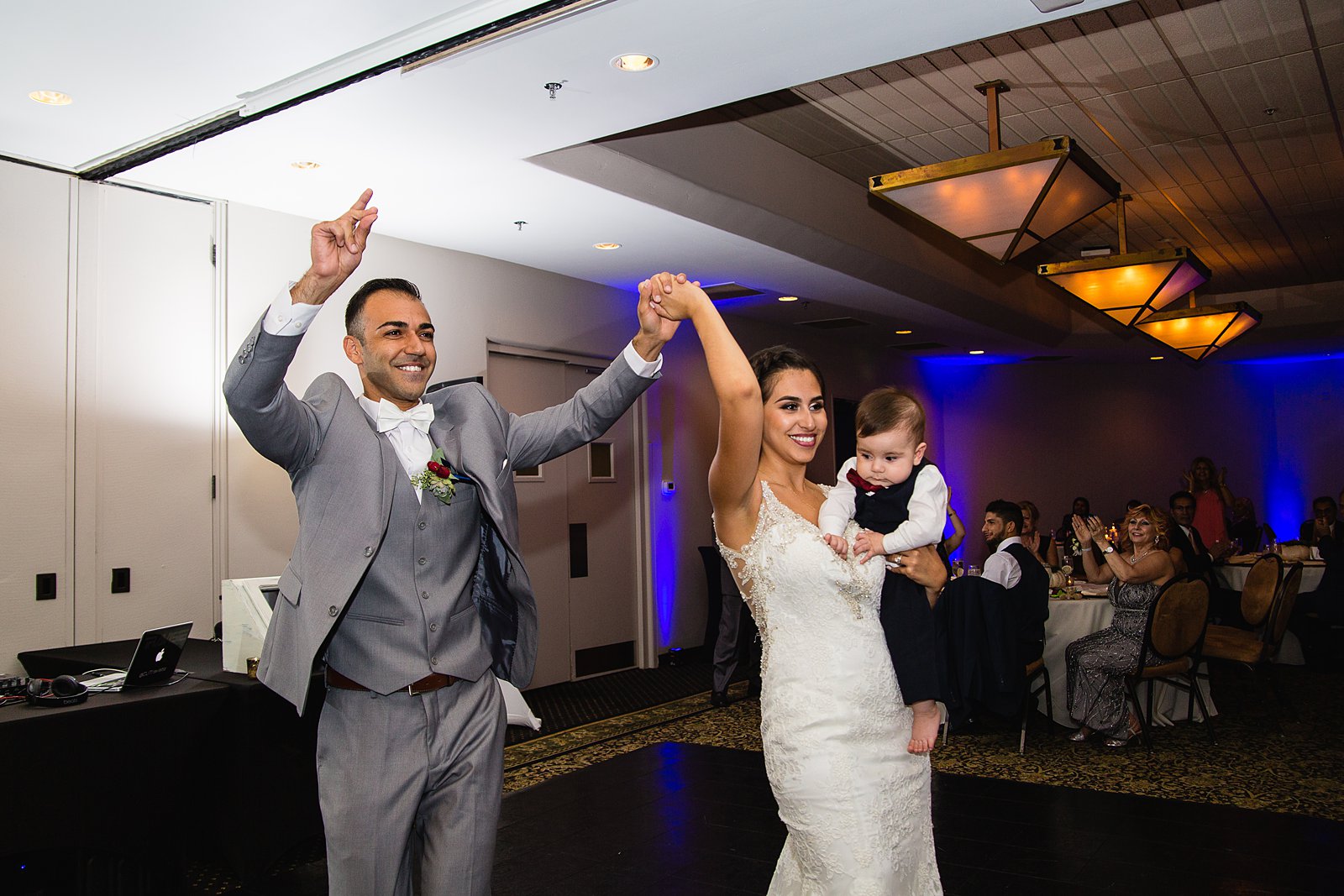 Bride and groom's grand entrance to their reception with their son by PMA Photography.