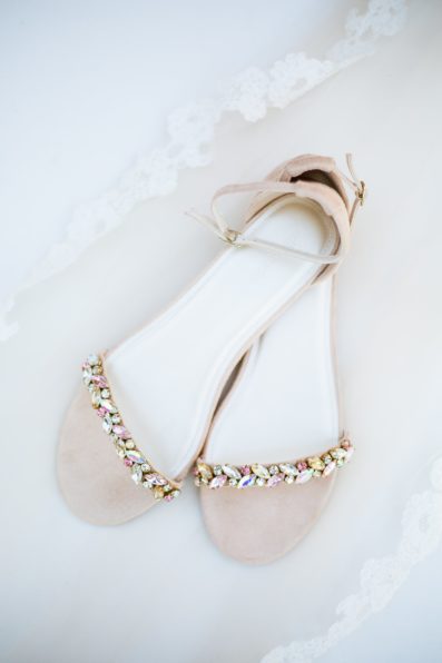 Brides's wedding day details of rose gold bridal flats by PMA Photography.