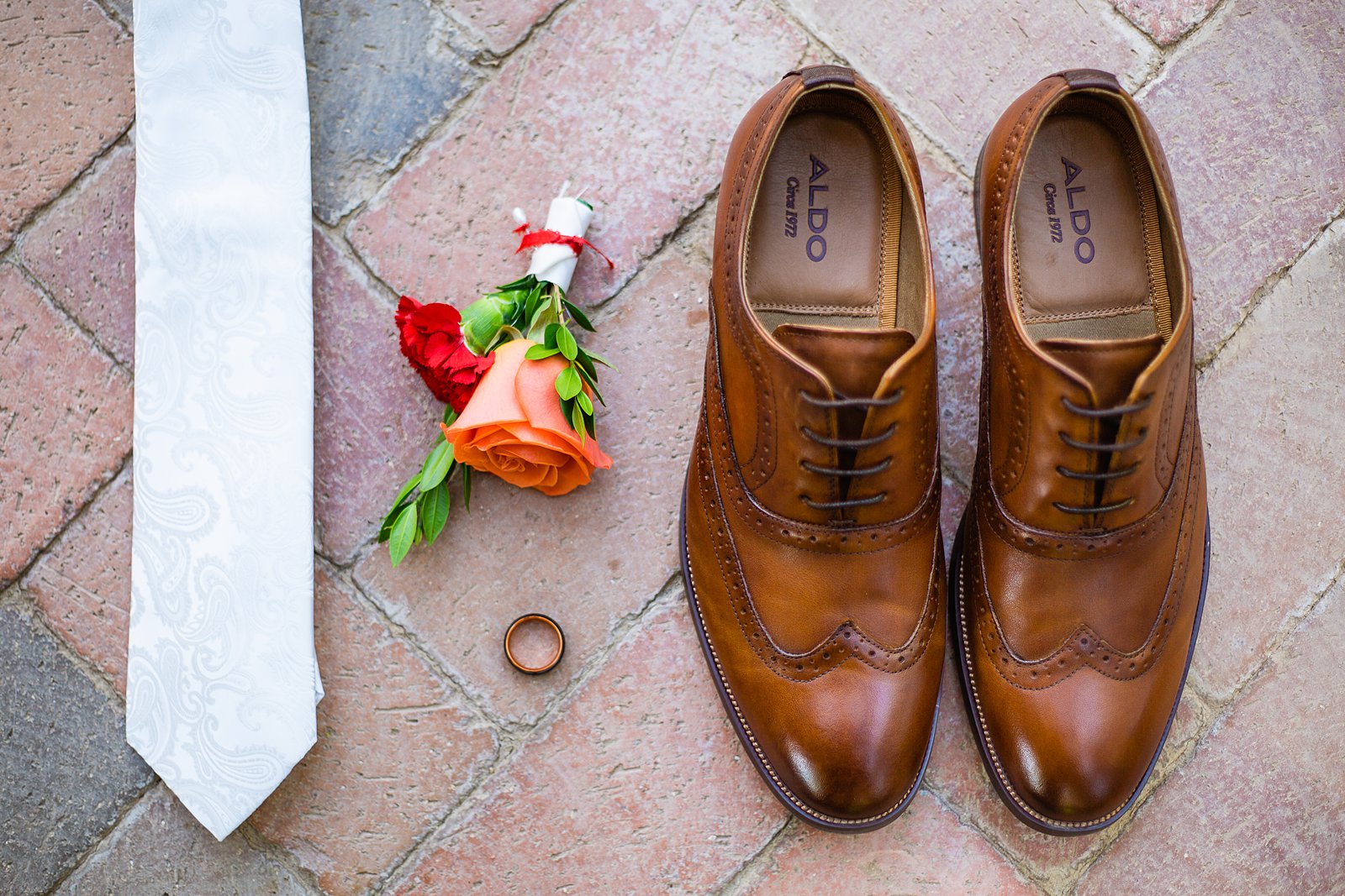 Groom's wedding day details of a white tie, colorful boutonniere, brown leather oxford shoes, and Manly Bands wedding ring by PMA Photography.