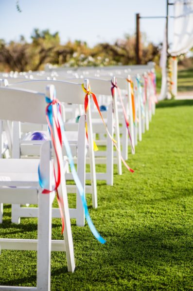 Colorful fiesta ribbon on chairs at a wedding ceremony at The Farmhouse at Schnepf Farms by Arizona wedding photographer PMA Photography.