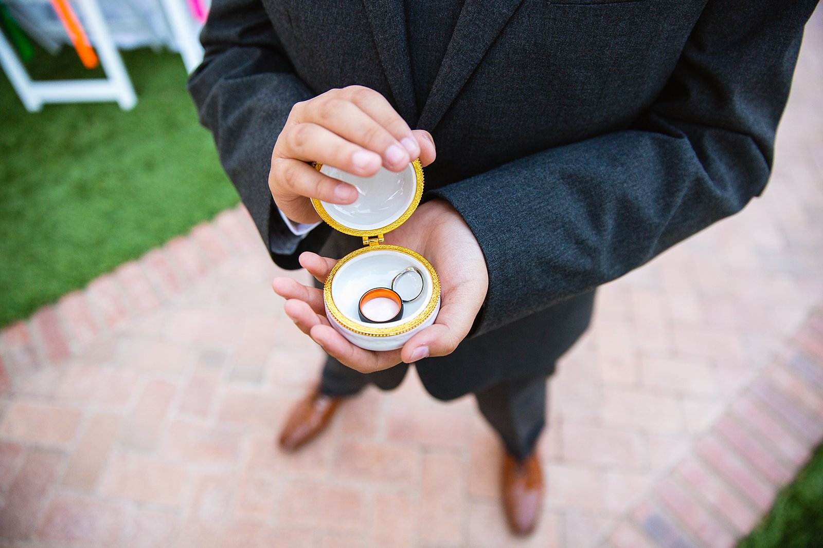 Ring bearer holding wedding bands in macaroon ring box by PMA Photography.