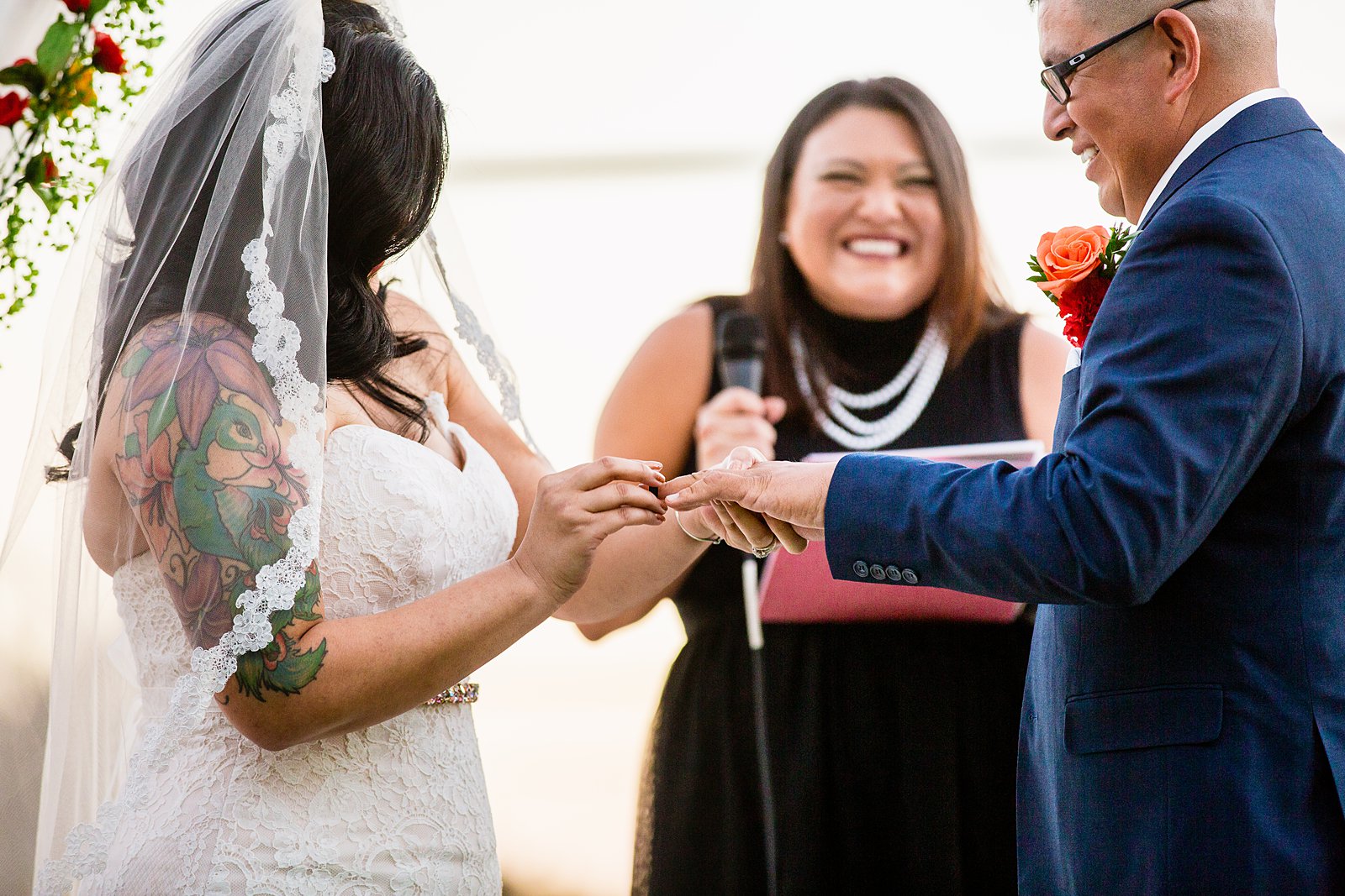 Bride and groom exchange rings during their wedding ceremony at The Farmhouse at Schnepf Farms by Arizona wedding photographer PMA Photography.