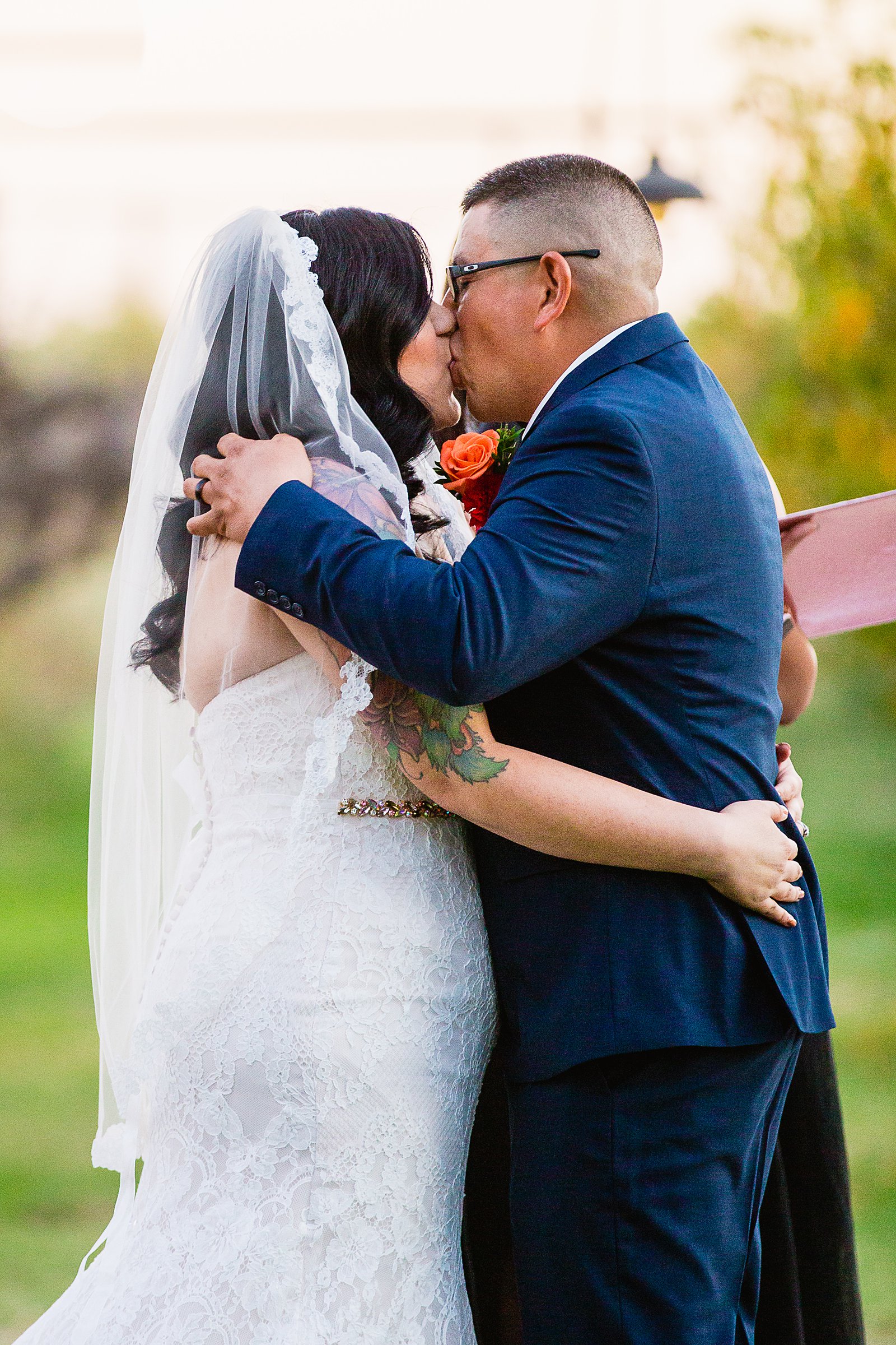 Bride and groom share their first kiss during their wedding ceremony at The Farmhouse at Schnepf Farms by Arizona wedding photographer PMA Photography.