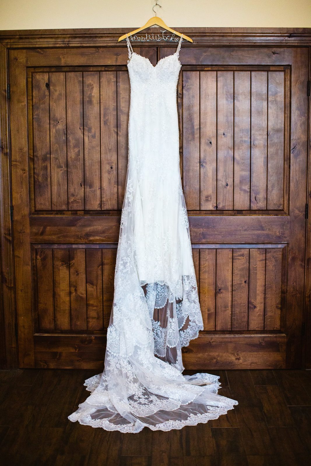 Bride's romantic lace wedding dress on custom Mrs. wooden hanger by PMA Photography.