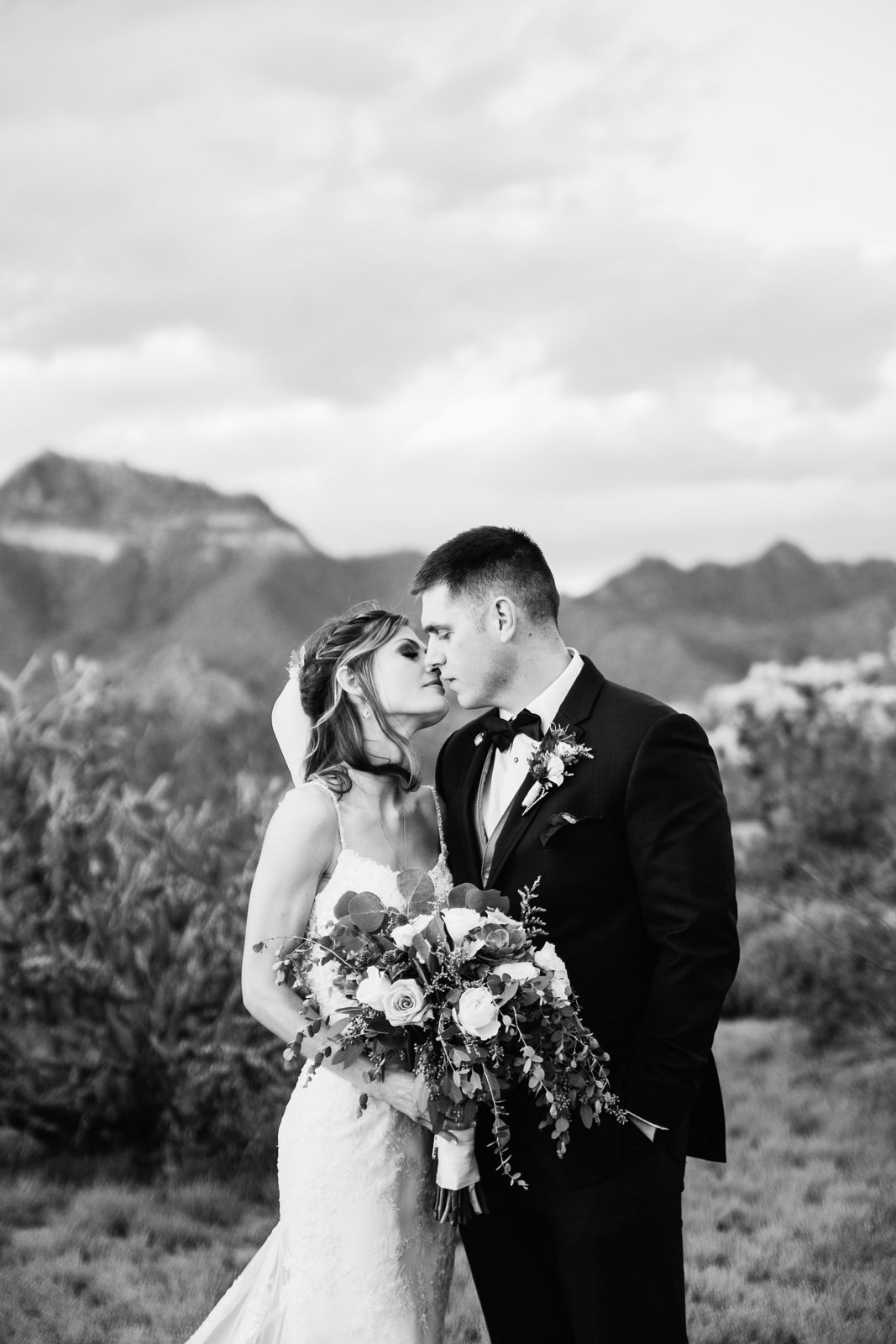 Bride and groom share a romantic moment in the desert on their wedding day by Arizona wedding photographer PMA Photography.