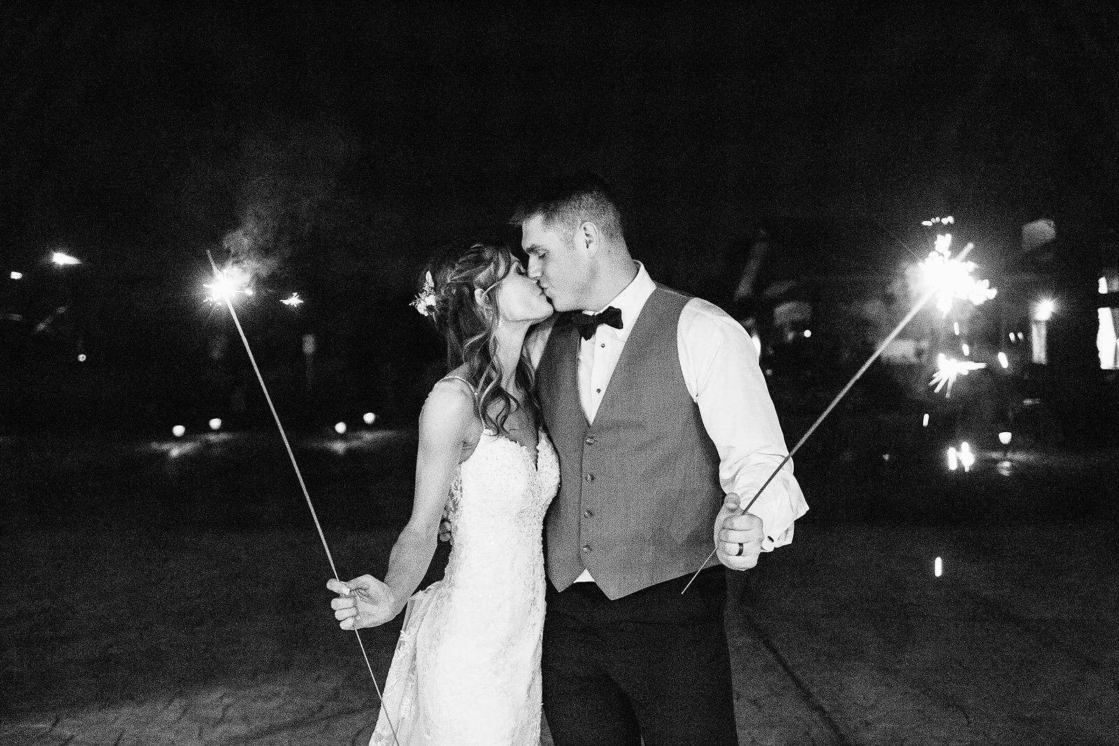 Bride and groom kiss with sparklers at their Superstition Manor wedding reception by Arizona wedding photographer PMA Photography.