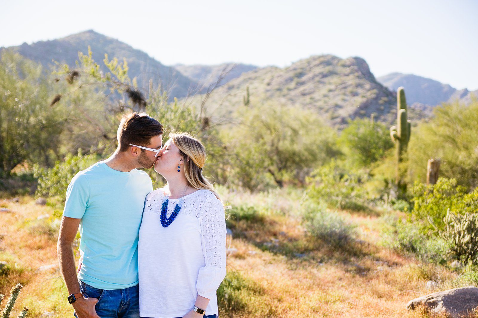 Couple share a kiss during their White Tanks desert engagement session by Wadell wedding photographer PMA Photography.