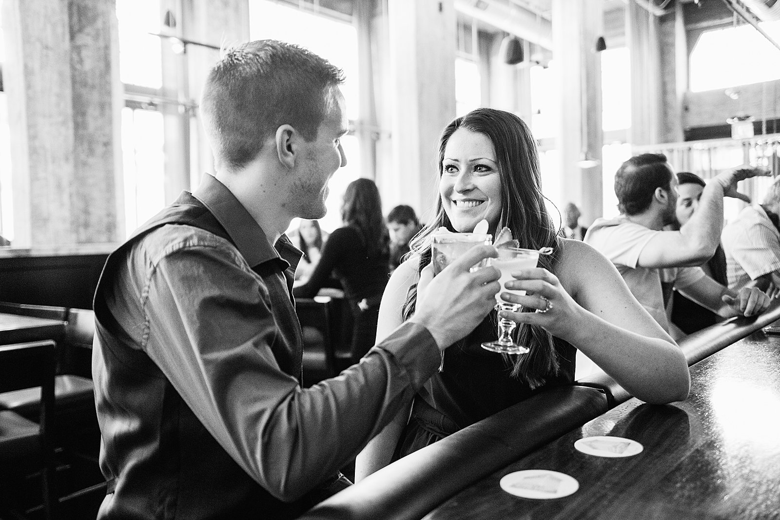 Couple share a toast during their Downtown Phoenix bar engagement session by Phoenix wedding photographer PMA Photography.