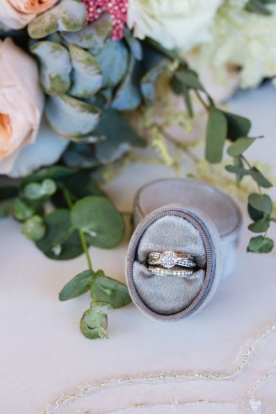 Brides's wedding day details of simple white gold wedding ring with bouquet by PMA Photography.