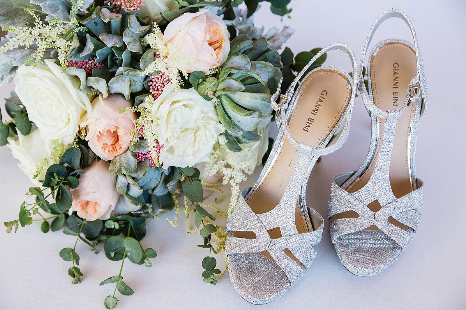 Brides's wedding day details of silver Gianni Bini shoes with green and blush bouquet. by PMA Photography.