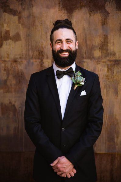 Groom in a classic tux with a succulent boutonniere and a man bun by Arizona wedding photographer PMA Photography.