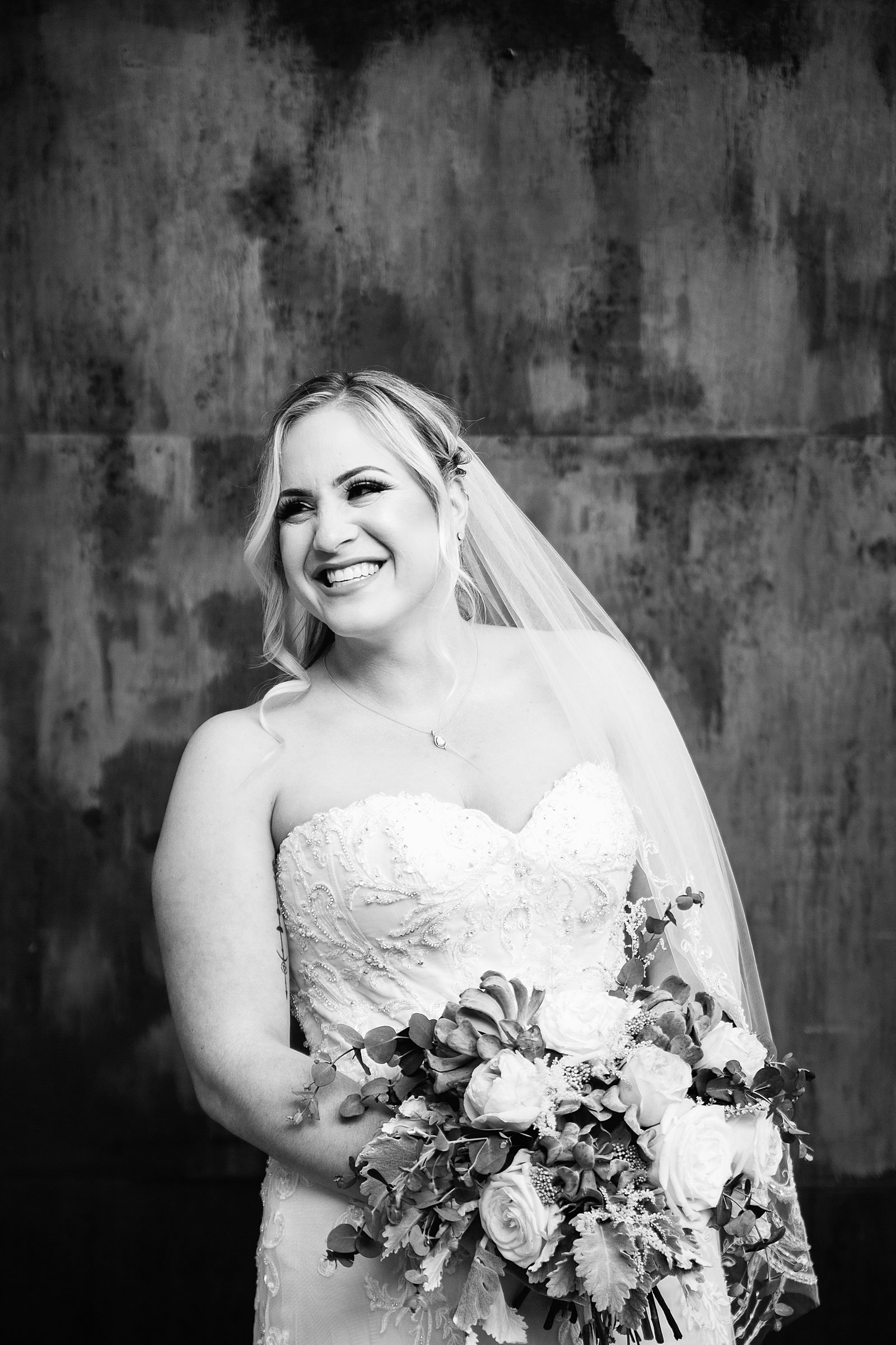 Bride in a romantic wedding dress with a succulent bouquet laughing on her wedding day by Phoenix wedding photographer PMA Photography.