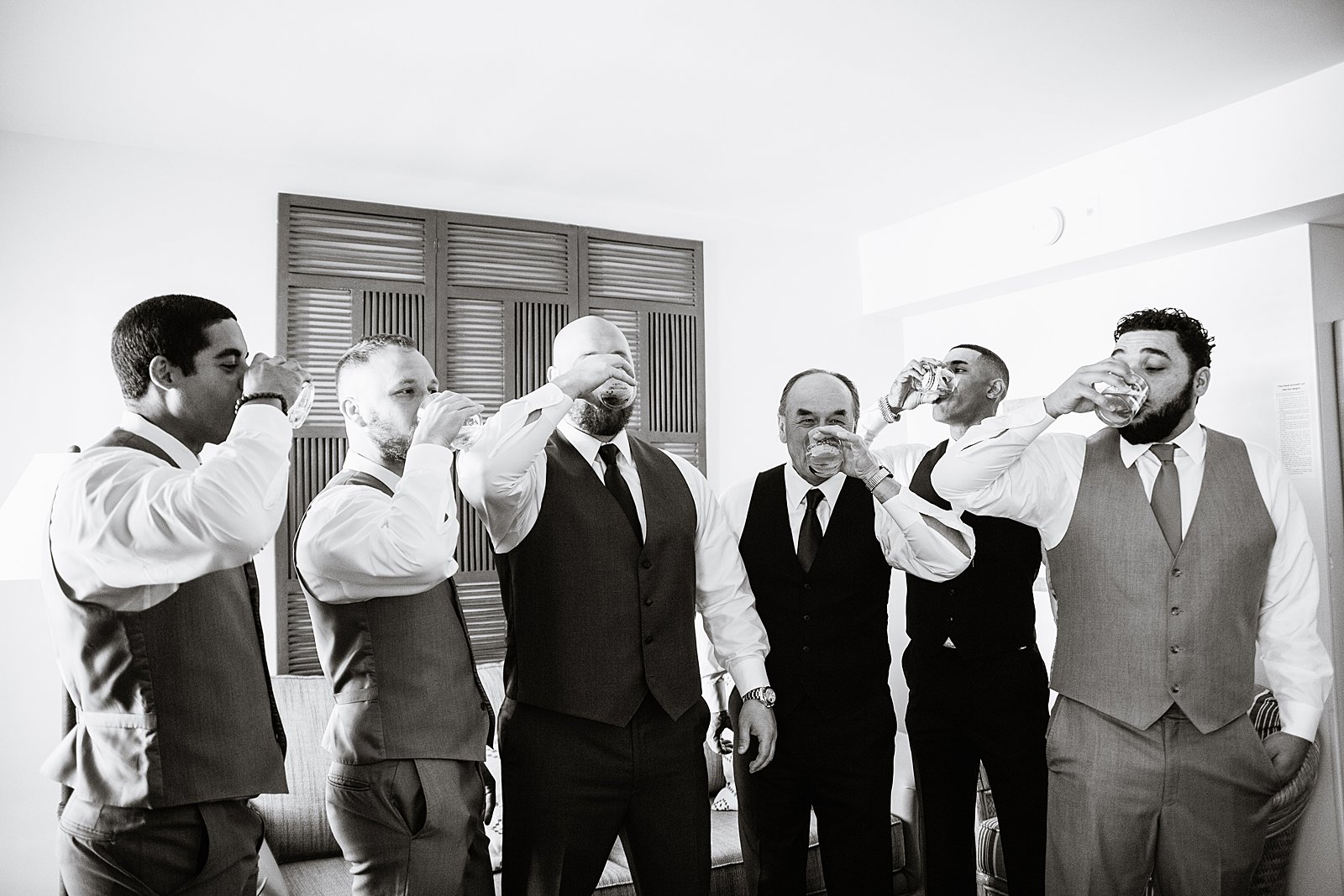 Groom toasting with guests while getting ready for his wedding by Phoenix wedding photographers PMA Photography.
