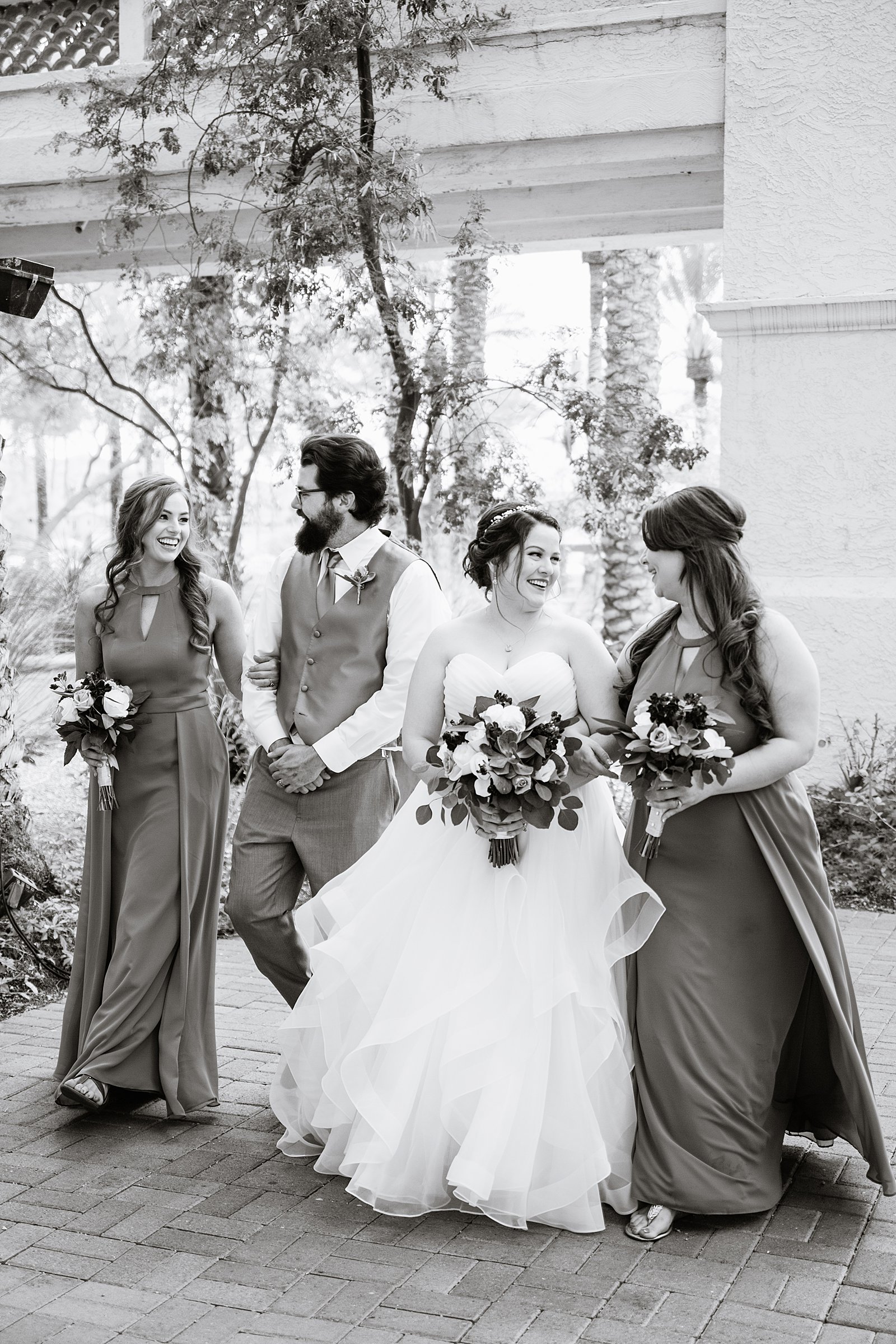 Bride and mixed gender bridal party laughing together at a Arizona Grand Resort wedding by Arizona wedding photographer PMA Photography.