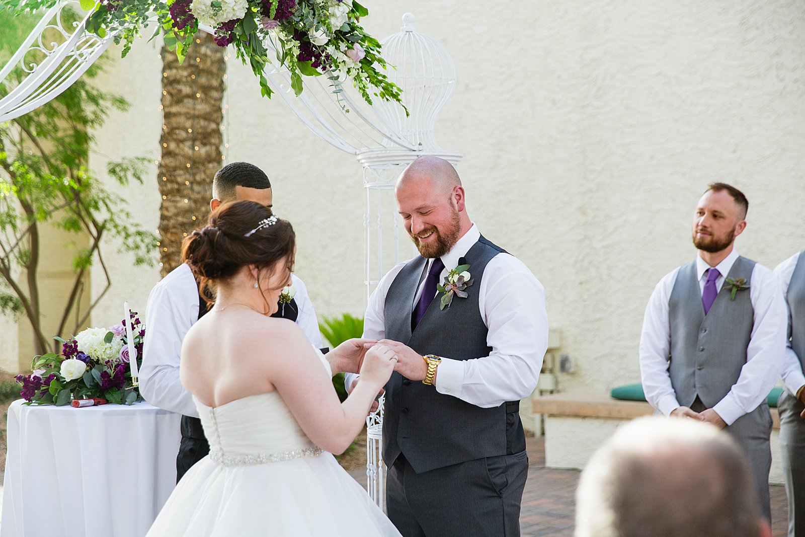 Bride and Groom exchange rings during their wedding ceremony at Arizona Grand Resort by Phoenix wedding photographer PMA Photography.