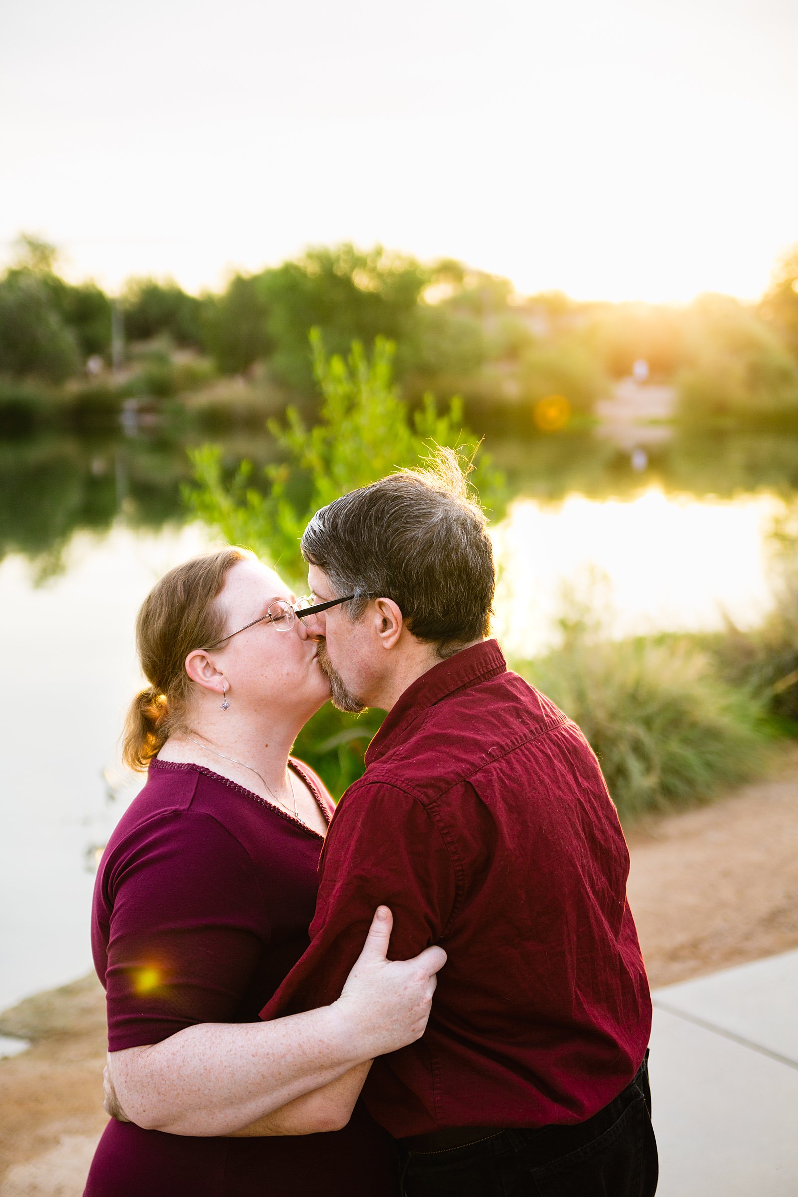 Couple share a kiss during their Veterans Oasis Park engagement session by Gilbert wedding photographer PMA Photography.