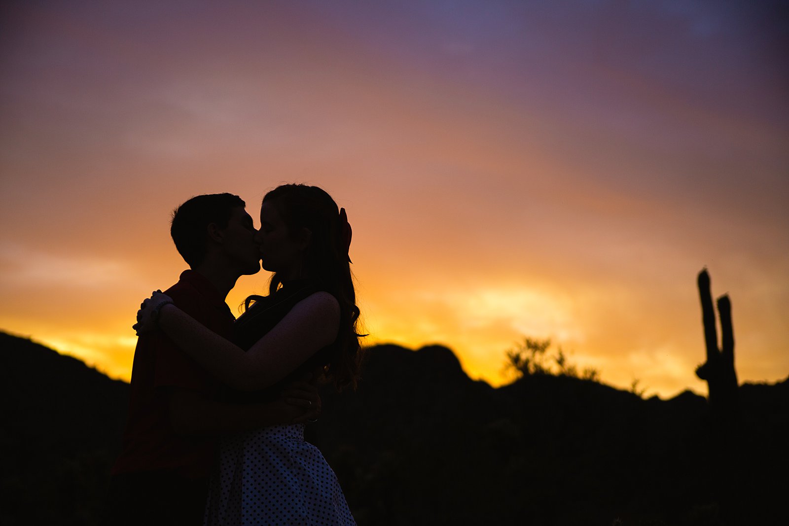 Couple share a kiss at sunset during their Phoenix anniversary session by Arizona wedding photographer PMA Photography.