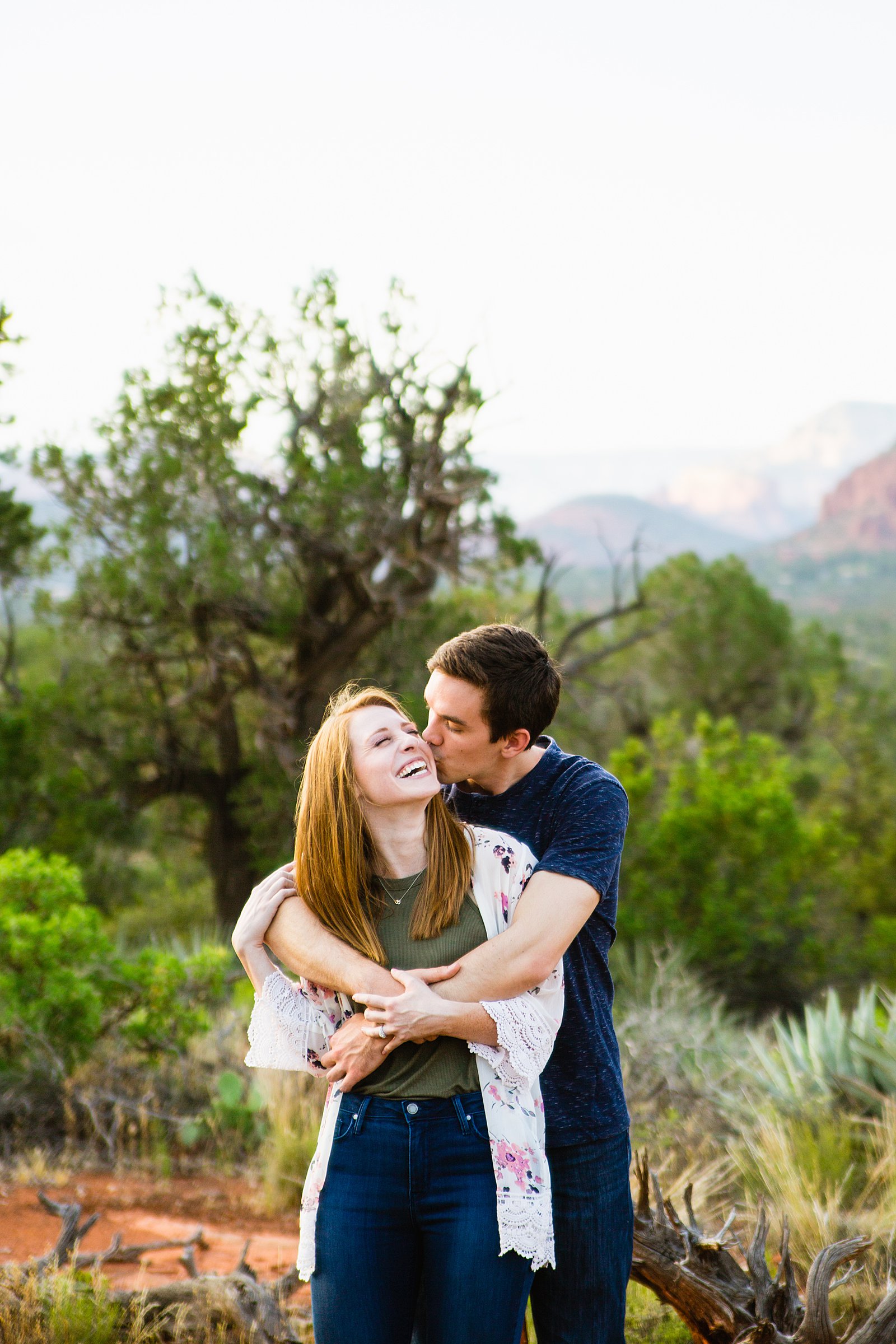 Couple laugh together during their Bell Rock engagement session by Sedona engagement photographer PMA Photography.