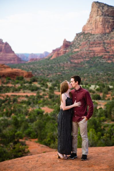 Adventurous couple share a kiss during their Sedona engagement session by Arizona wedding photographer PMA Photography.
